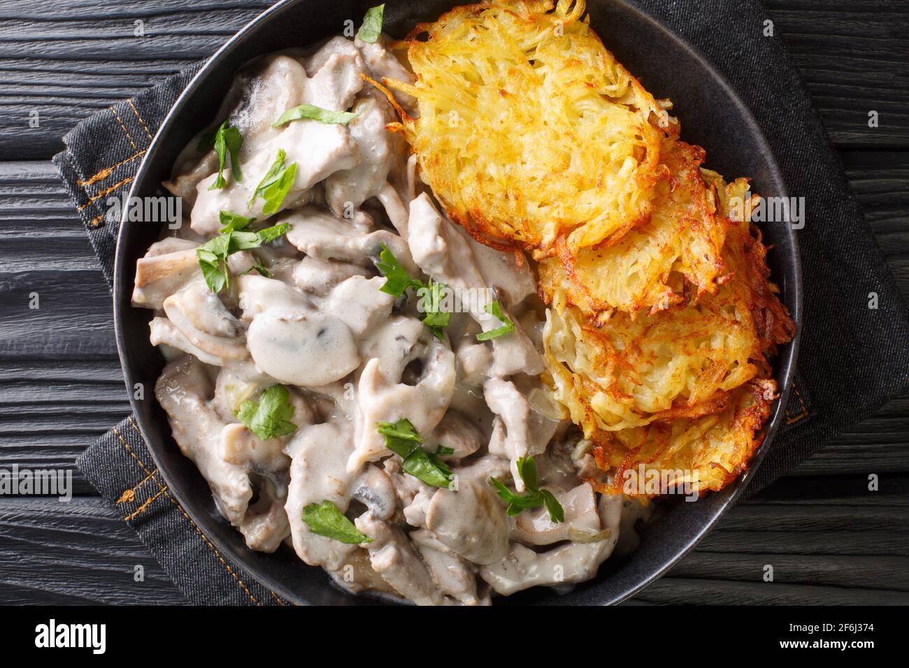 Swiss Zurich veal with mushrooms in a creamy sauce with potato pancakes close-up in a plate on the table. horizontal top view from above Stock Photo