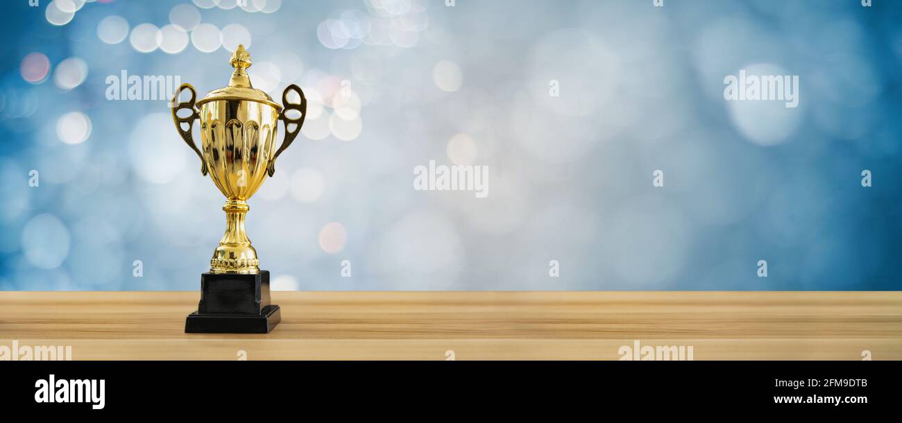 1st champion award, the best prize and winner concept, championship cup or winner trophy on wood table with soft blue and bokeh background Stock Photo