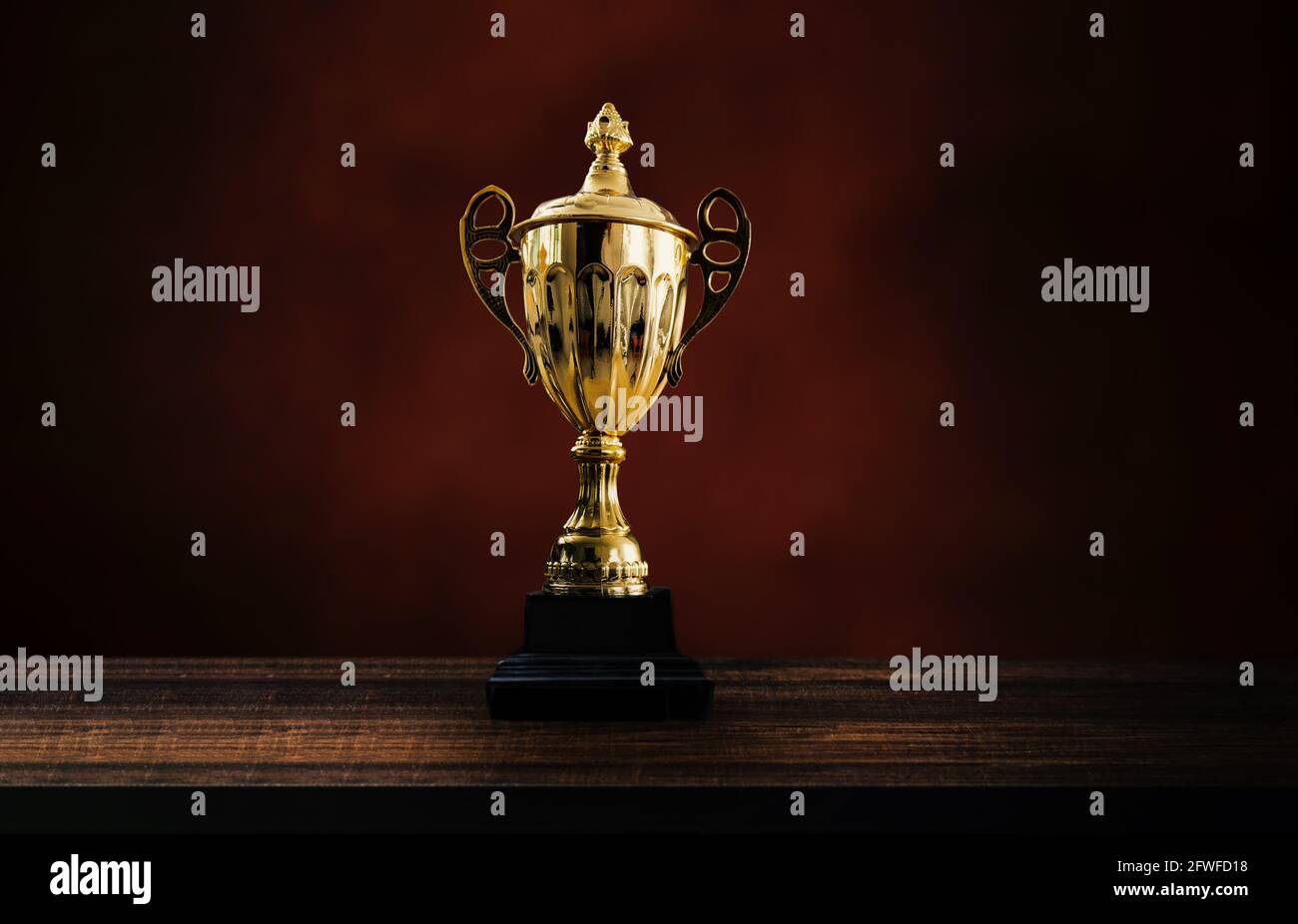 1st champion award, the best prize and winner concept, championship cup or winner trophy on wood table on black and dark brown wall background Stock Photo