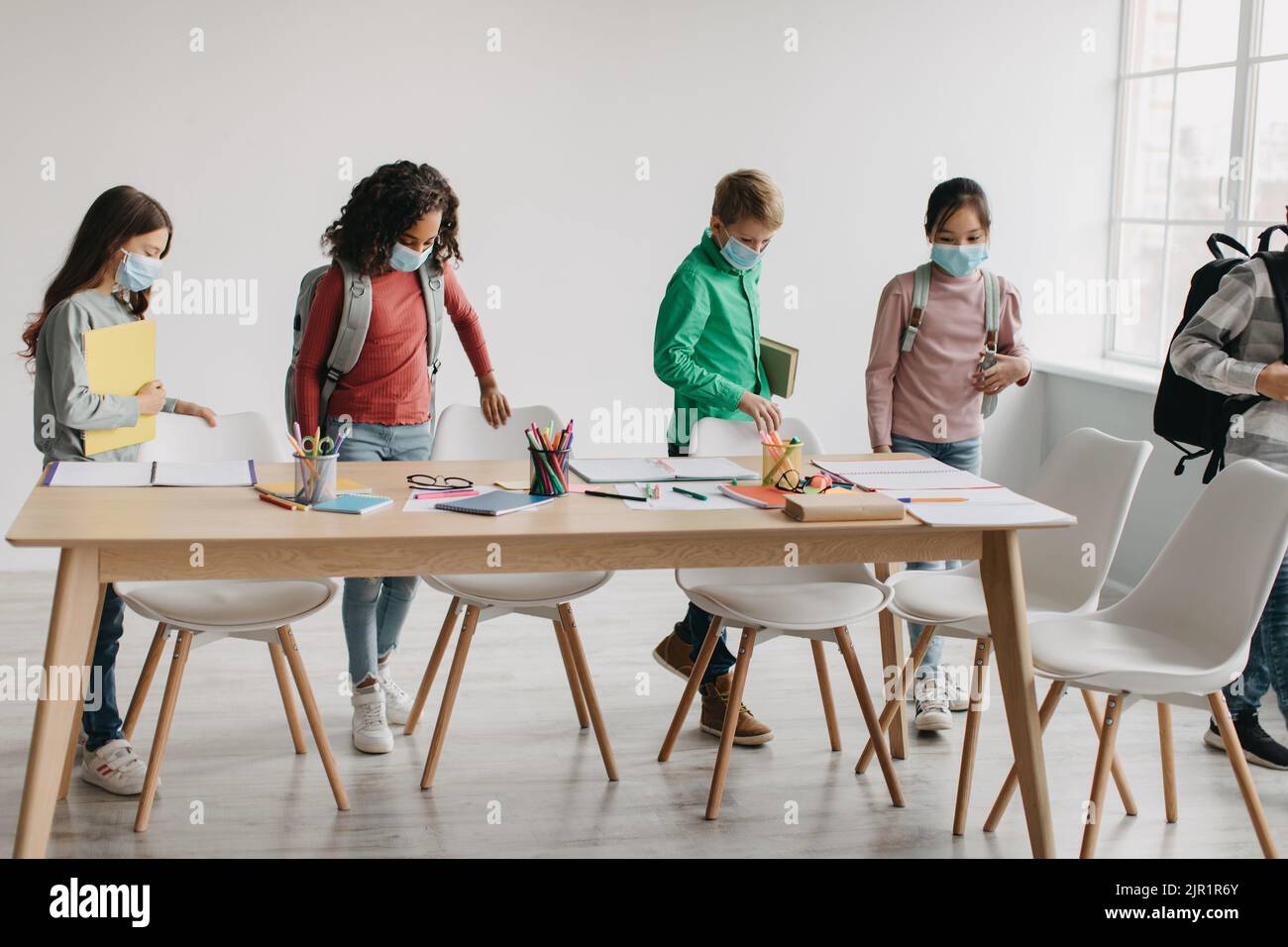 Multiracial Pupils Kids Wearing Face Masks Carrying Backpacks Entering Classroom Stock Photo