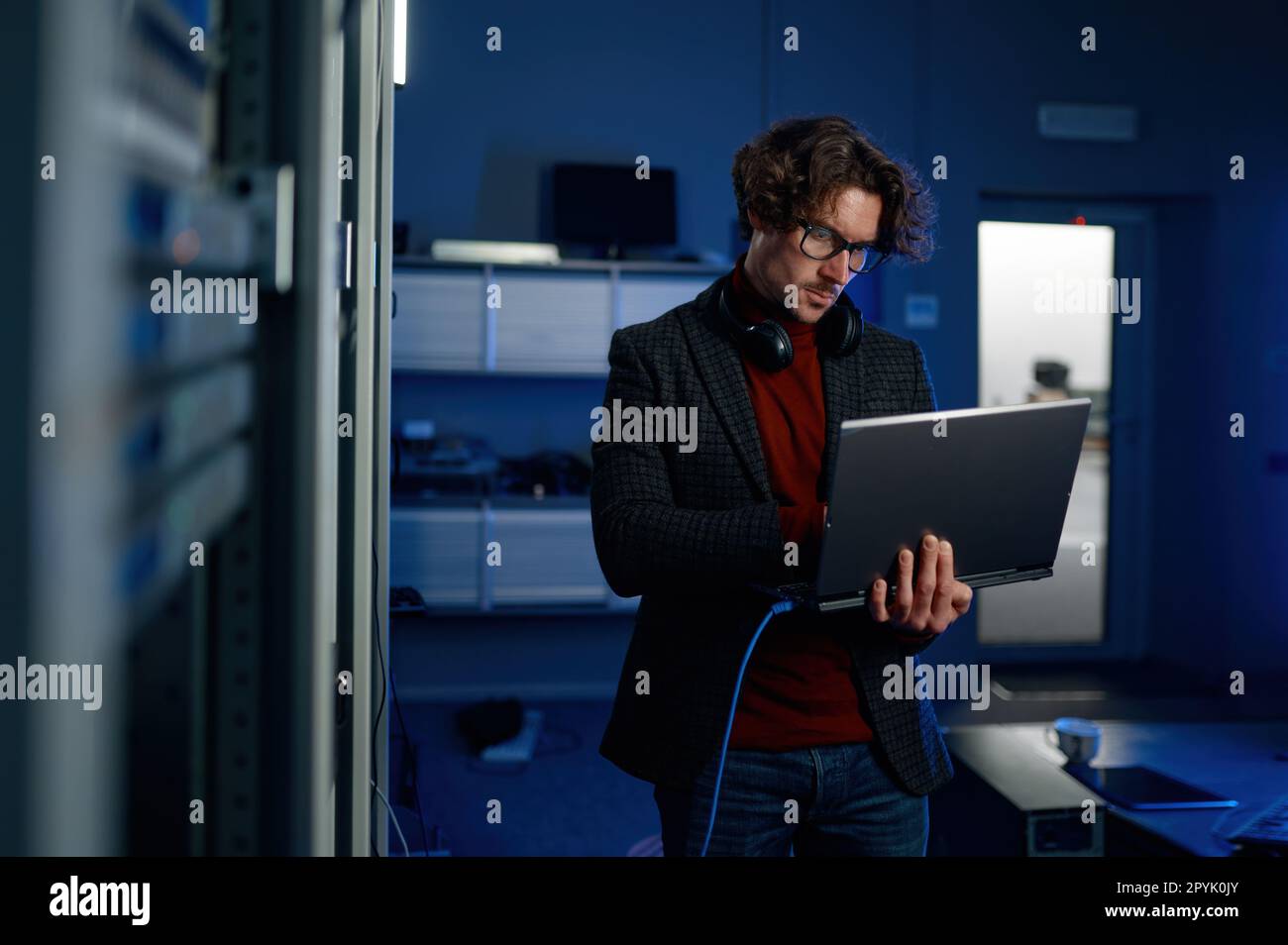 Data engineer holding laptop while working with supercomputer in server room Stock Photo