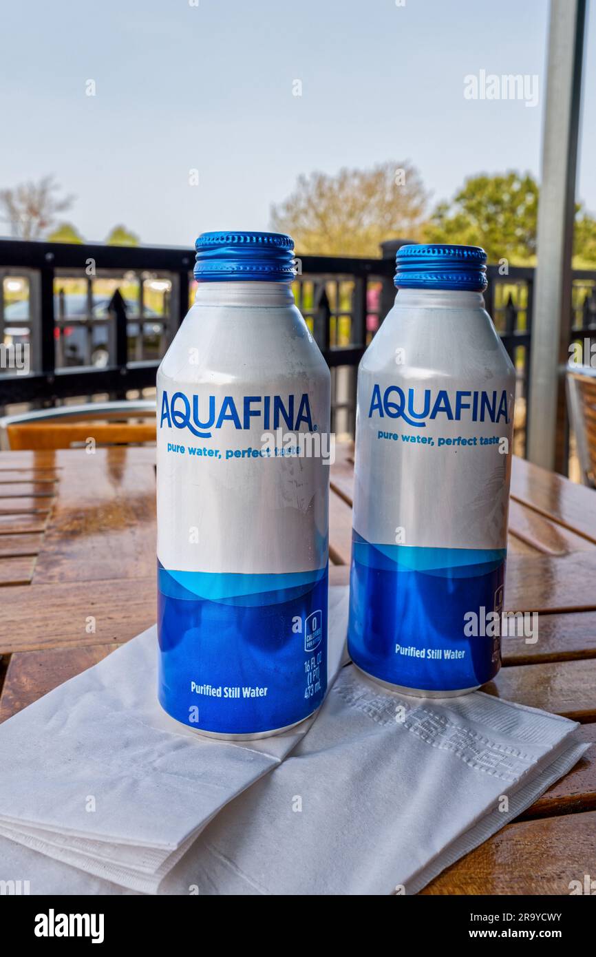 Sandwich, MA - May 11, 2023: Ice cold aluminum bottles of Aquafina purified water on a patio dining table. The aluminum bottles are part of an initiat Stock Photo