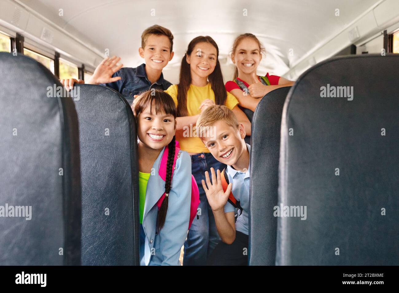 Diverse happy cheerful kids having fun inside a school bus Stock Photo