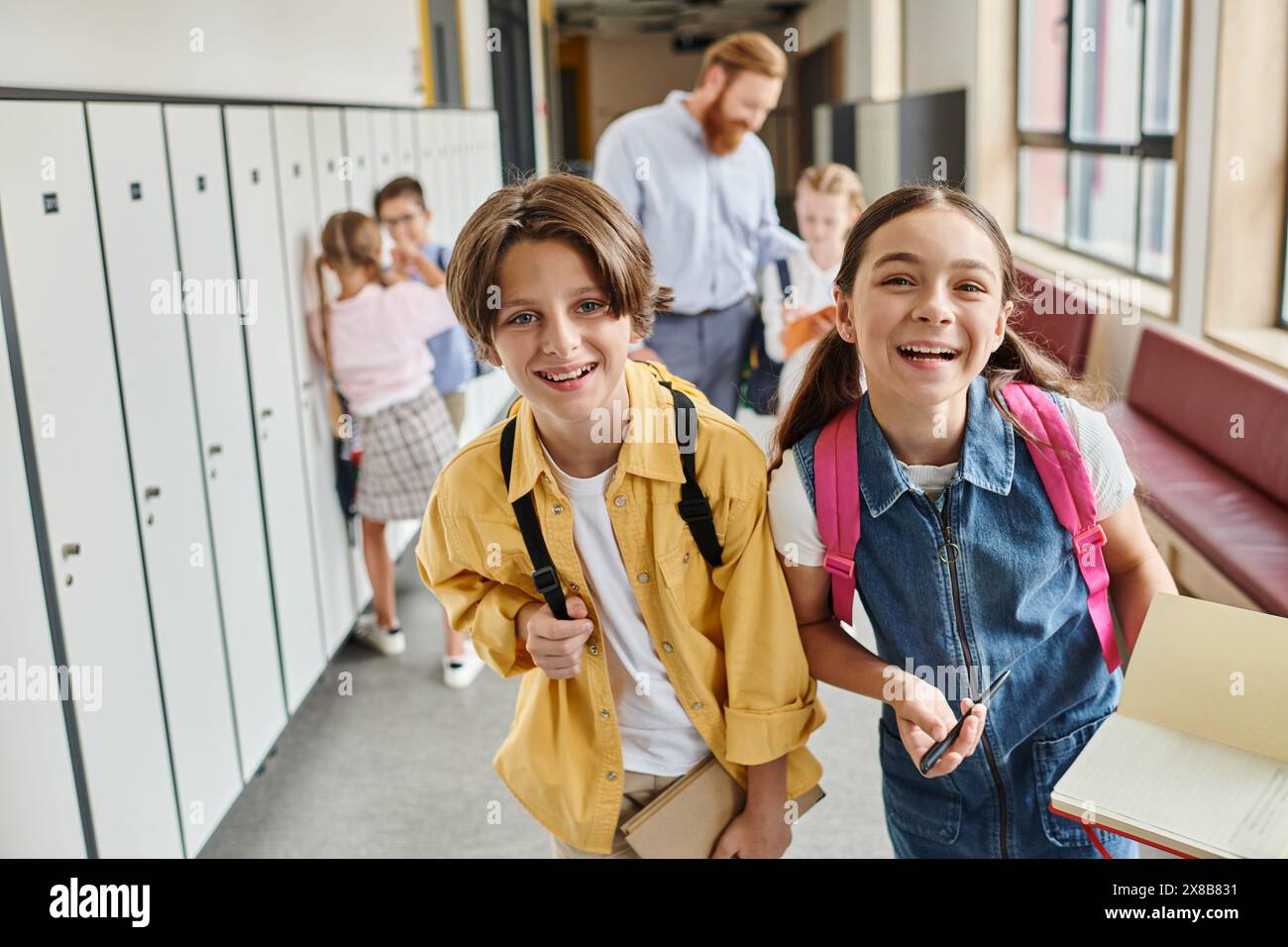 A diverse group of kids walk down a school hallway filled with colorful lockers, chatting and laughing as they head to their next class. Stock Photo