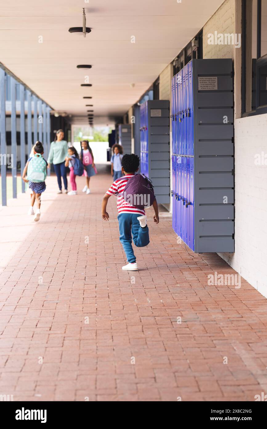 In school, diverse children are walking down hallway with lockers with copy space outdoors Stock Photo