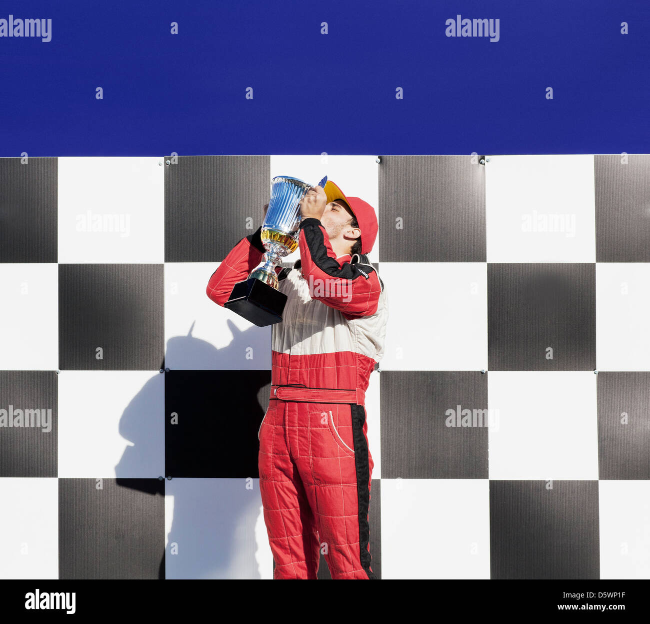 Racer kissing trophy at award ceremony Stock Photo