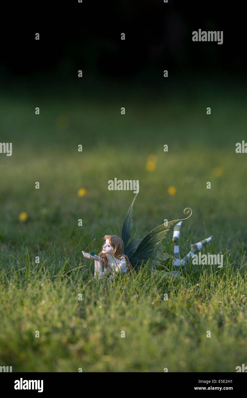 Fairy ornament in grass lit up by sunlight Stock Photo