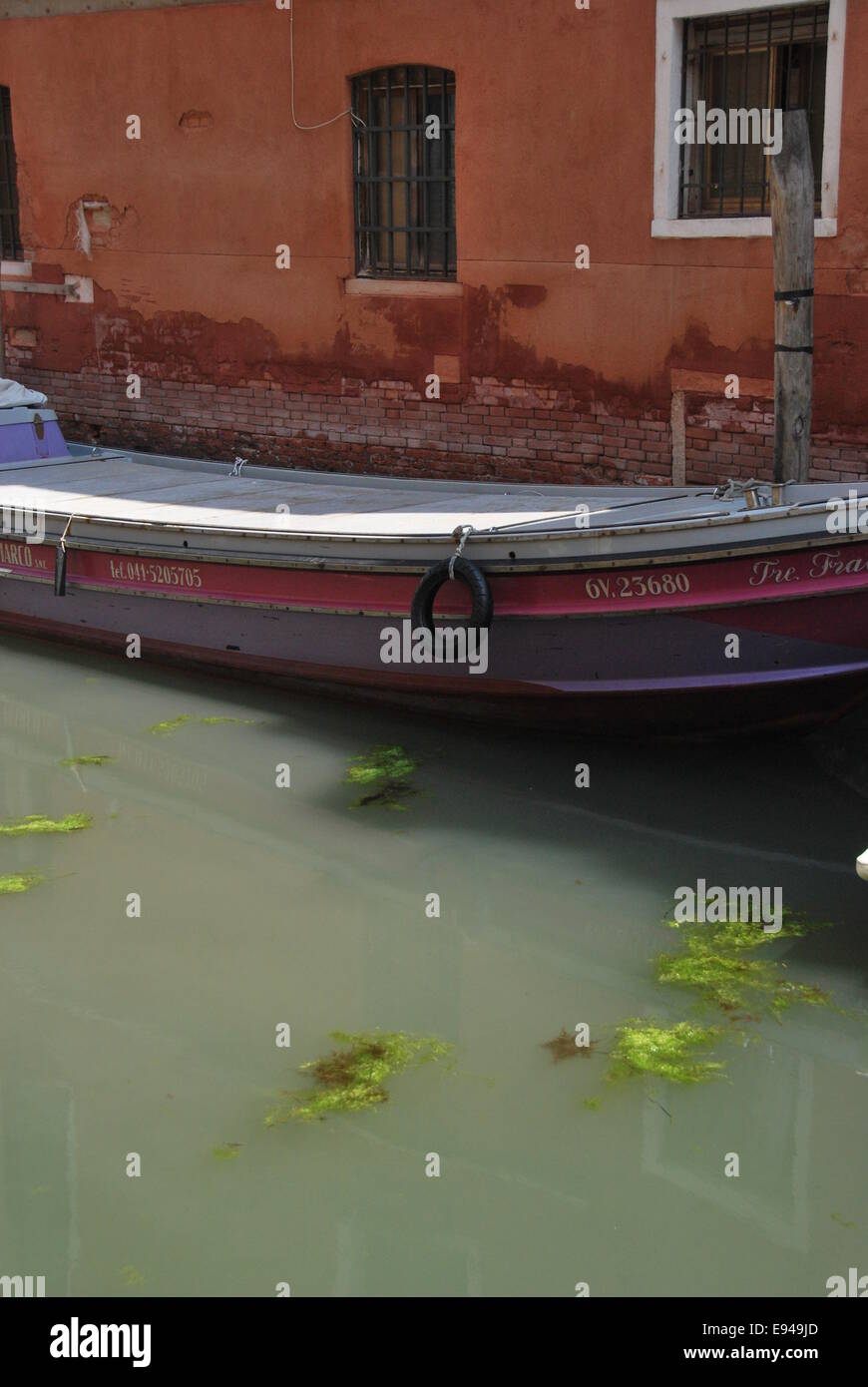 Italy. Venice. canal scene. old boat. worn wood, crumbling brickwork.  reflections, movement. calm. Stock Photo