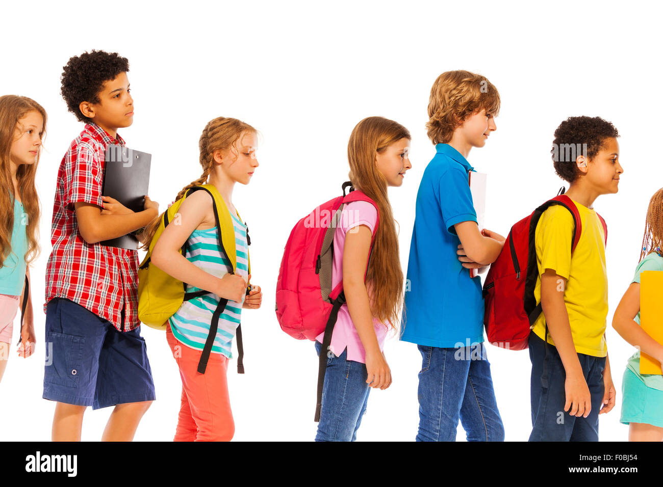 School kids go in line with backpacks profile view Stock Photo