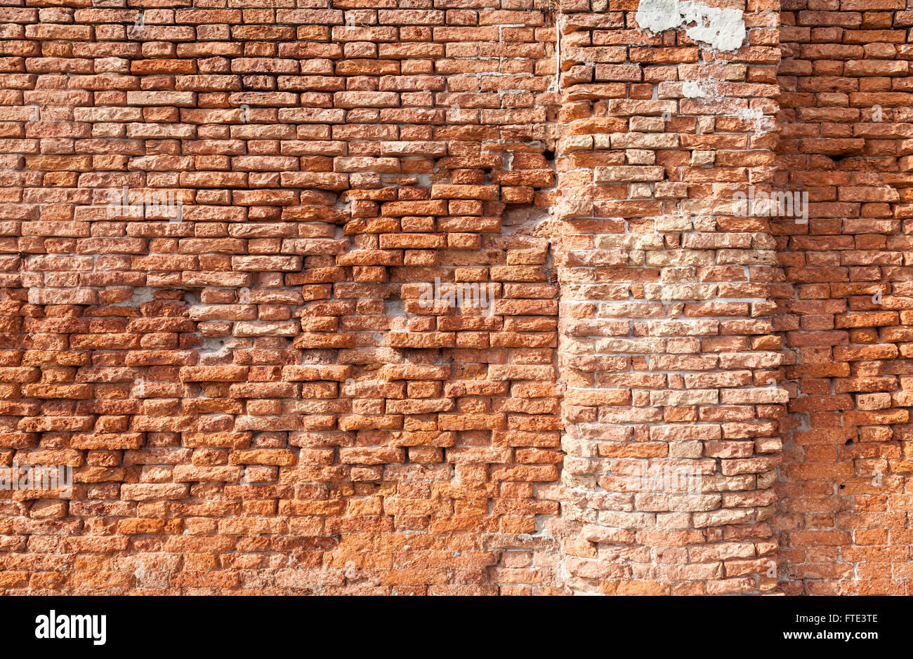 Richly warm coloured crumbling brickwork in a brightly sunlit wall along Fondamemta al Saloni in Venice, Italy Stock Photo