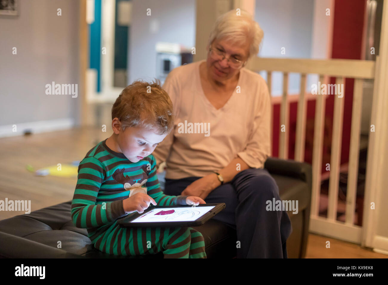 Wheat Ridge, Colorado - Susan Newell, 69, watches as her grandson, Adam Hjermstad Jr., 3, plays an educational game on an iPad before bedtime. Stock Photo