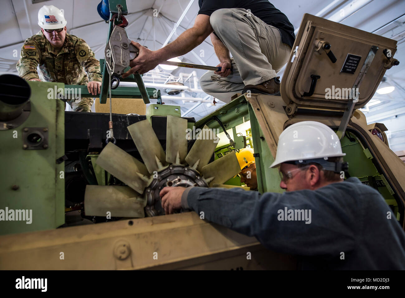 Civilian instructors work with U.S. Army Reserve mechanics from across the 200th Military Police Command to reinstall the engine to an M117 Armored Security Vehicle (ASV) during a maintenance course hosted by the 99th Readiness Division in Schenectady, New York, March 14, 2018. This is the first maintenance course in the U.S. Army Reserve designed specifically for the ASV, which has hydraulic components and maintenance procedures that are unlike most other Army vehicles. The ASV is designed to resist the impact of roadside bombs while operating in urban environments. Its mounting systems allow Stock Photo