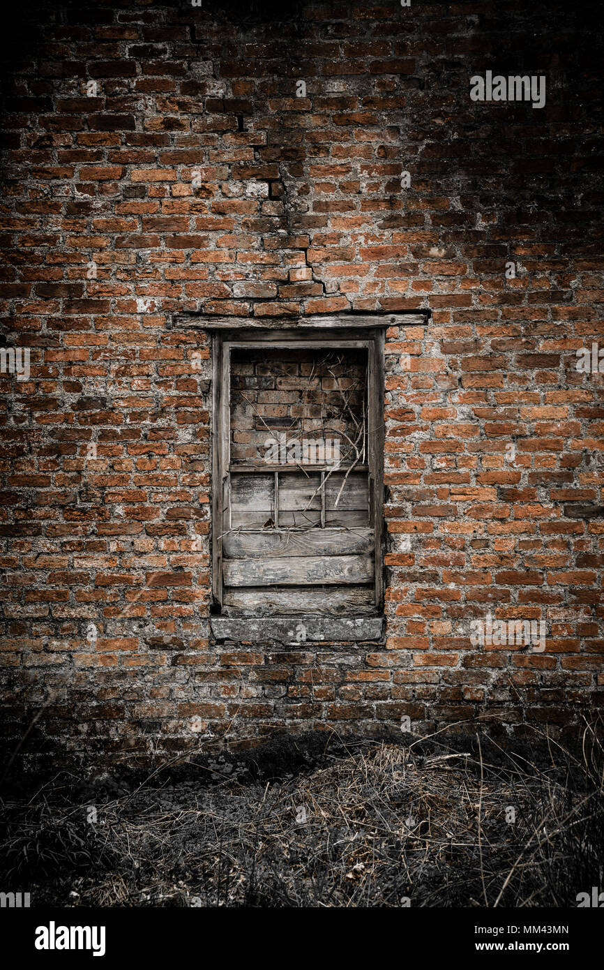 bricked and boarded up broken window in an ancient  brickwork wall Stock Photo