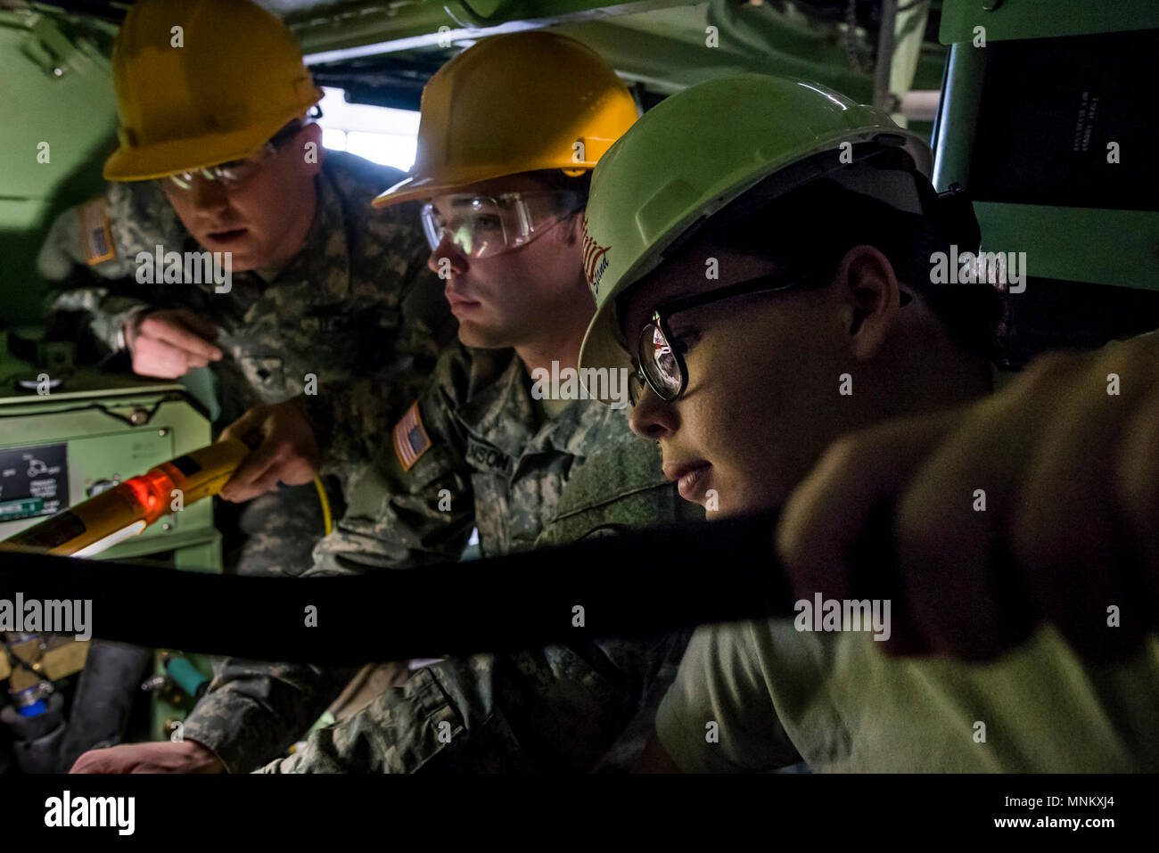 Cpl. Cala Reardon (right), Spc. Wyatt Hanson and Spc. John Williams, U.S. Army Reserve mechanics from across the 200th Military Police Command, work to reattach fuel and power lines to the engine while working inside the crammed space of an M117 Armored Security Vehicle (ASV) during a maintenance course hosted by the 99th Readiness Division in Schenectady, New York, March 14, 2018. This is the first maintenance course in the U.S. Army Reserve designed specifically for the ASV, which has hydraulic components and maintenance procedures that are unlike most other Army vehicles. The ASV is designe Stock Photo