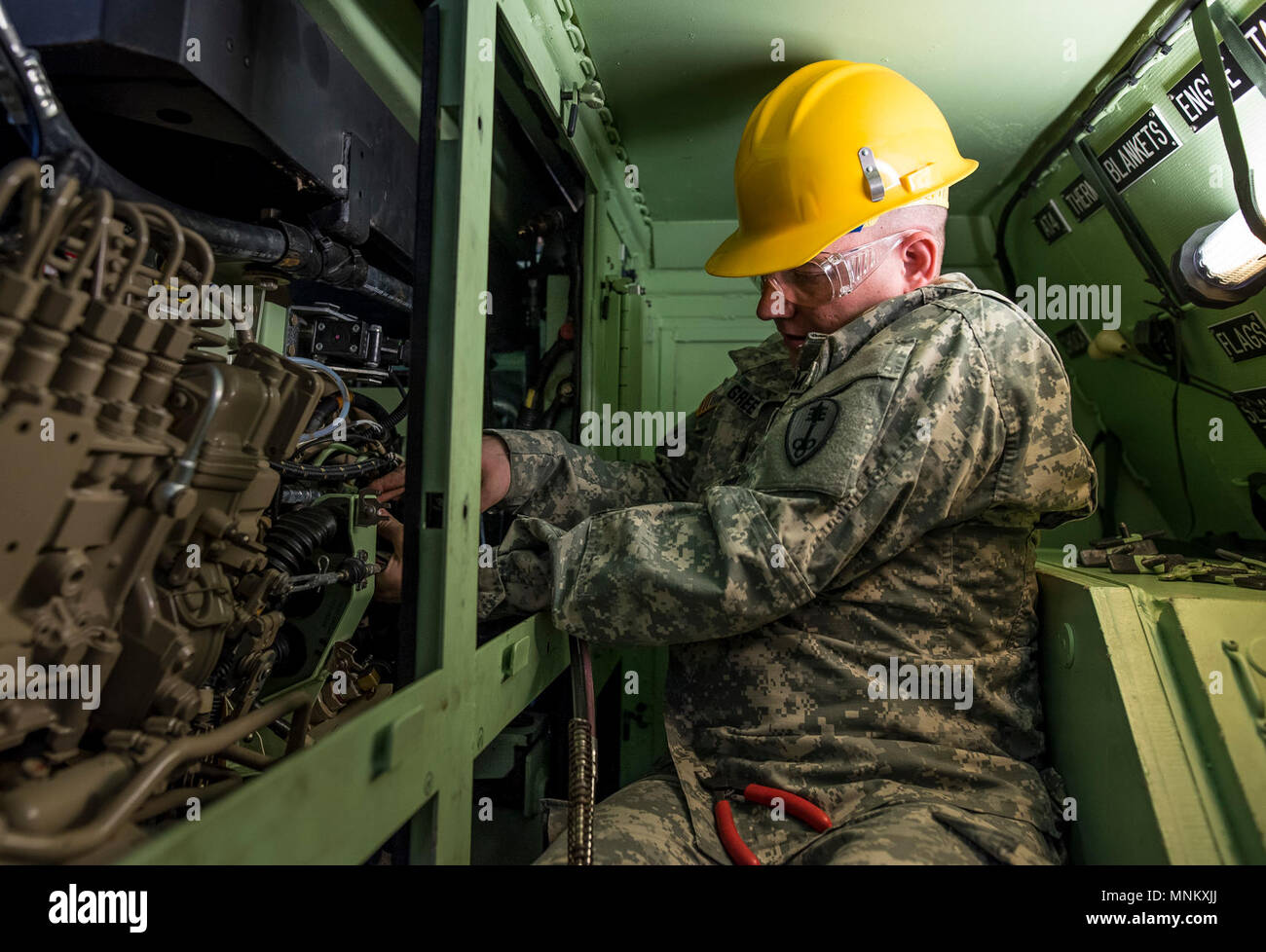 Sgt. Thomas Green, a U.S. Army Reserve mechanic with the 447th Military Police Company (Combat Support), out of North Canton, Ohio, works inside a small storage space to reattach lines to an entine on an M117 Armored Security Vehicle (ASV) during a maintenance course hosted by the 99th Readiness Division in Schenectady, New York, March 14, 2018. This is the first maintenance course in the U.S. Army Reserve designed specifically for the ASV, which has hydraulic components and maintenance procedures that are unlike most other Army vehicles. The ASV is designed to resist the impact of roadside bo Stock Photo