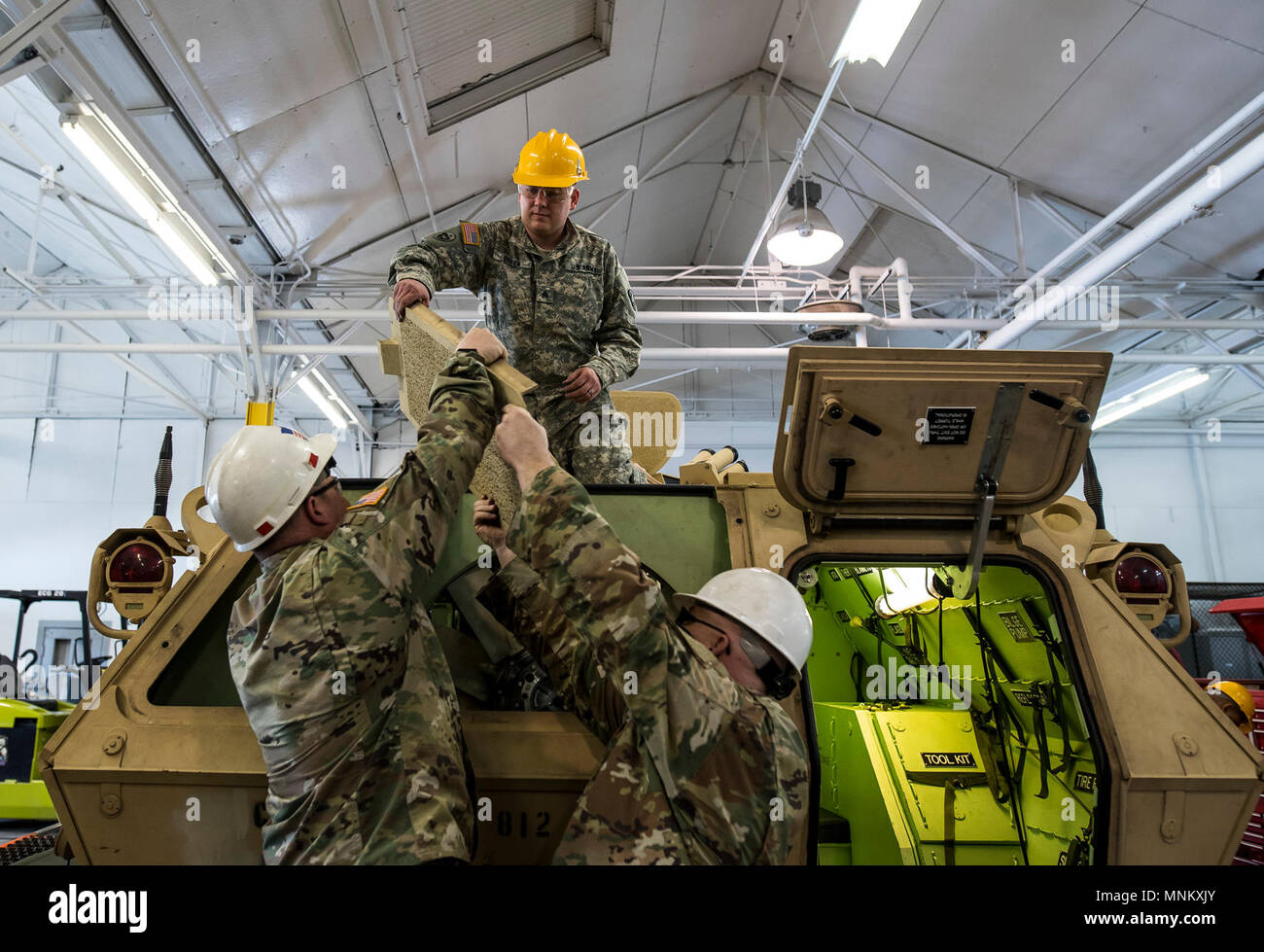 U.S. Army Reserve mechanics from across the 200th Military Police Command work to lift armored shield to reattach to an M117 Armored Security Vehicle (ASV) during a maintenance course hosted by the 99th Readiness Division in Schenectady, New York, March 14, 2018. This is the first maintenance course in the U.S. Army Reserve designed specifically for the ASV, which has hydraulic components and maintenance procedures that are unlike most other Army vehicles. The ASV is designed to resist the impact of roadside bombs while operating in urban environments. Its mounting systems allow the ASV to hol Stock Photo