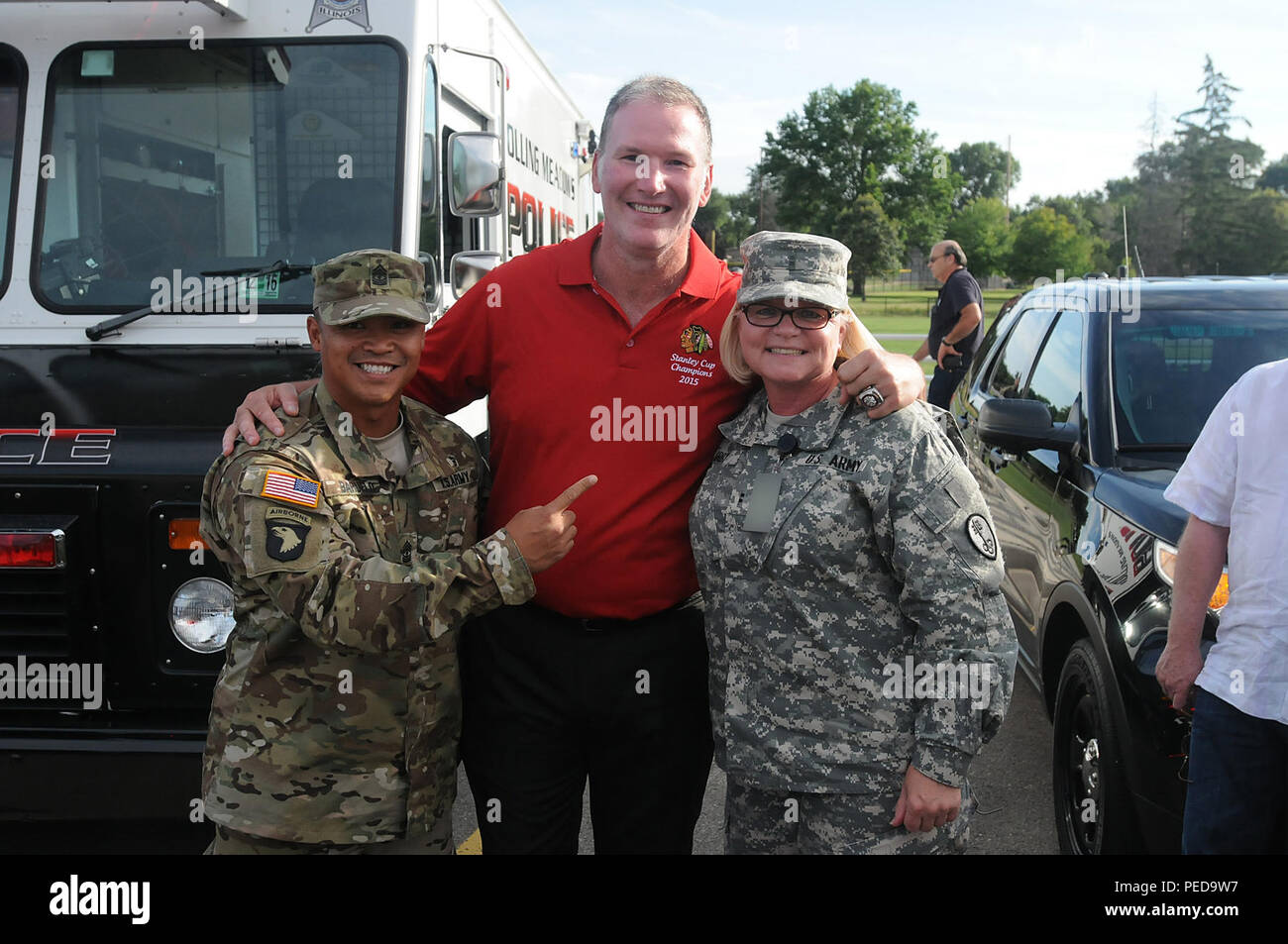 Army Reserve 1st. Sgt. Dominic Baruelo, left, and Chief Warrant Officer 2 Sabine Irby, right, both assigned to the 327th MP BN, 200th Military Police Command, pause for a photo with Chicago Blackhawks' national anthem singer, Jim Cornelison center, at the Rolling Meadows Police Department National Night Out community event, Aug. 4. Soldiers from the 85th Support Command also participated in the three-hour event here and simultaneously at the Village of Arlington Heights National Night Out event.  (U.S. Army photo by Spc. David Lietz/Released) Stock Photo