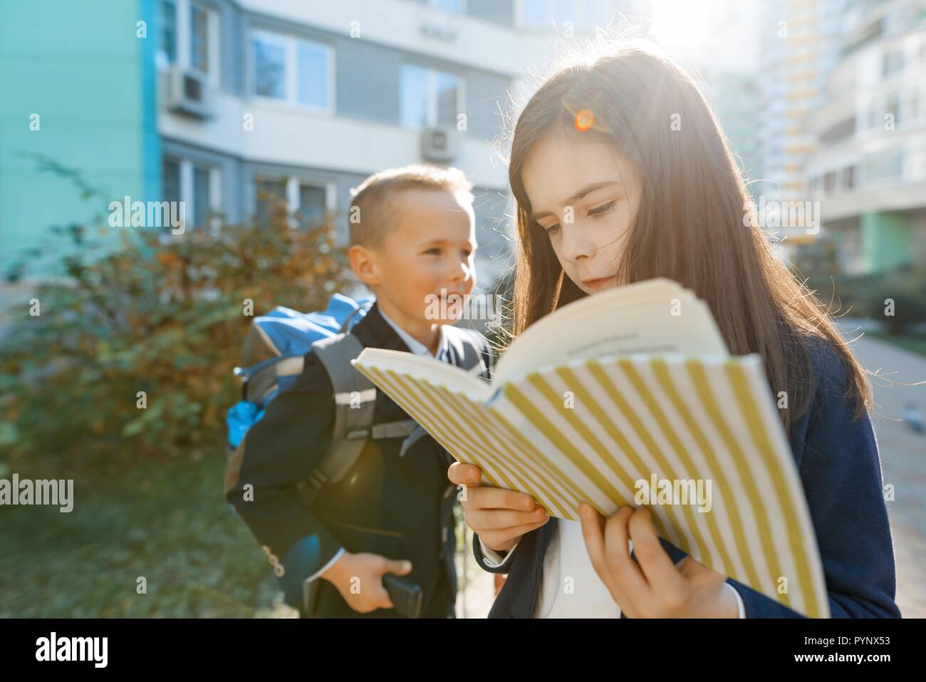 Outdoor portrait of smiling schoolchildren in elementary school. A group of kids with backpacks are having fun, talking. Education, friendship, techno Stock Photo