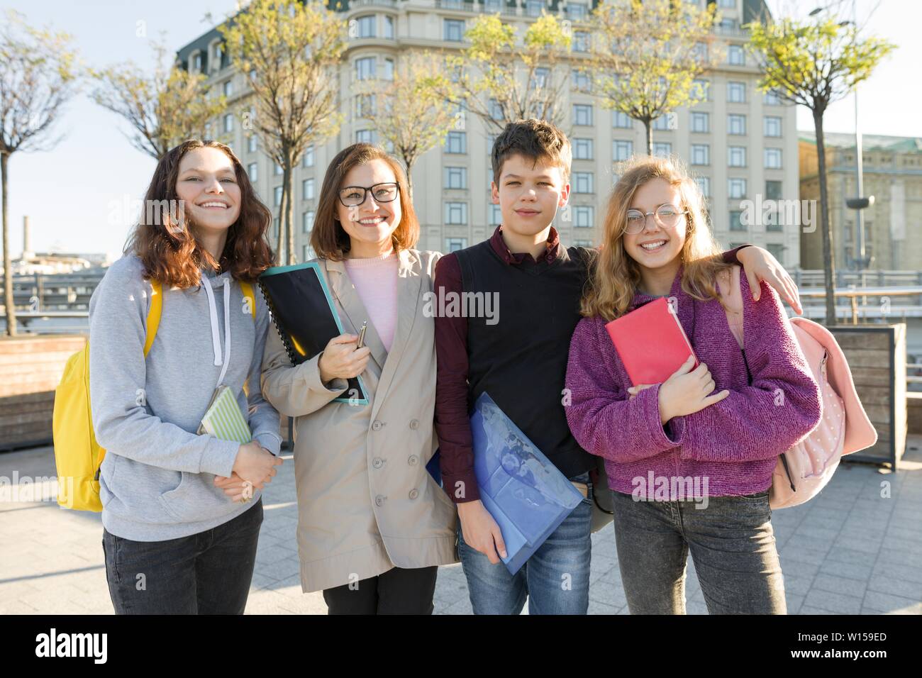 Group of students with teacher, teenagers talking to a female teacher, outdoor portrait Stock Photo