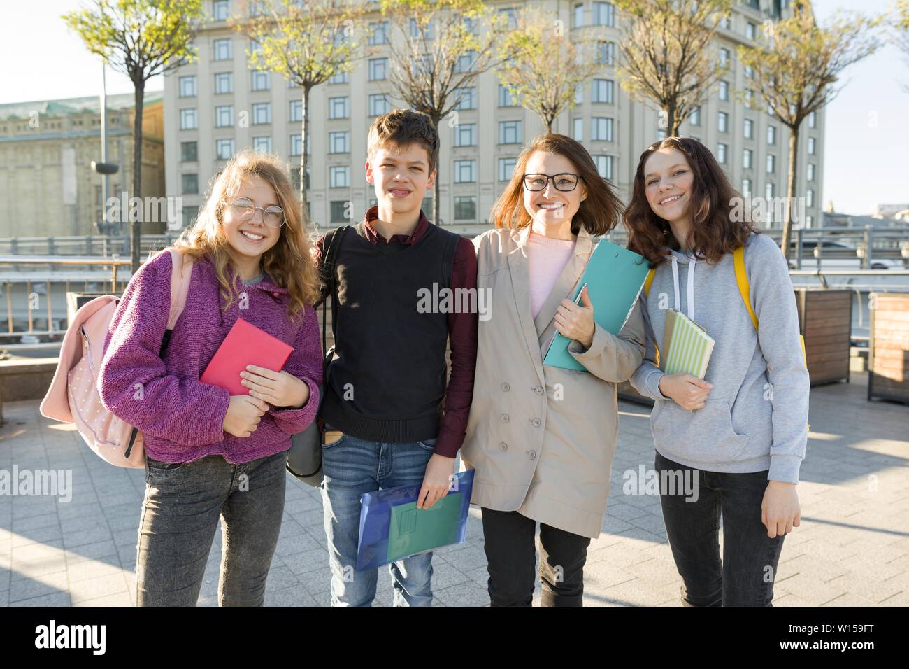 Group of students with teacher, teenagers talking to a female teacher, outdoor portrait Stock Photo