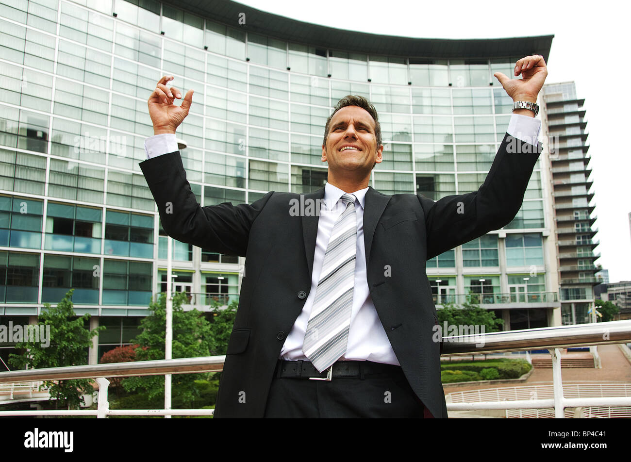 Business-Mann mit den Armen in der Luft, was darauf hindeutet, Leistung und Erfolg Stockfoto