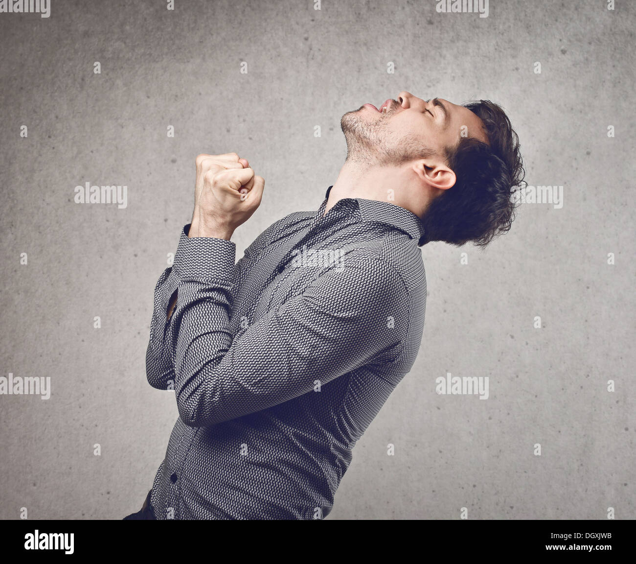 Junger Mann im grauen Shirt Jubel für seinen Erfolg Stockfoto