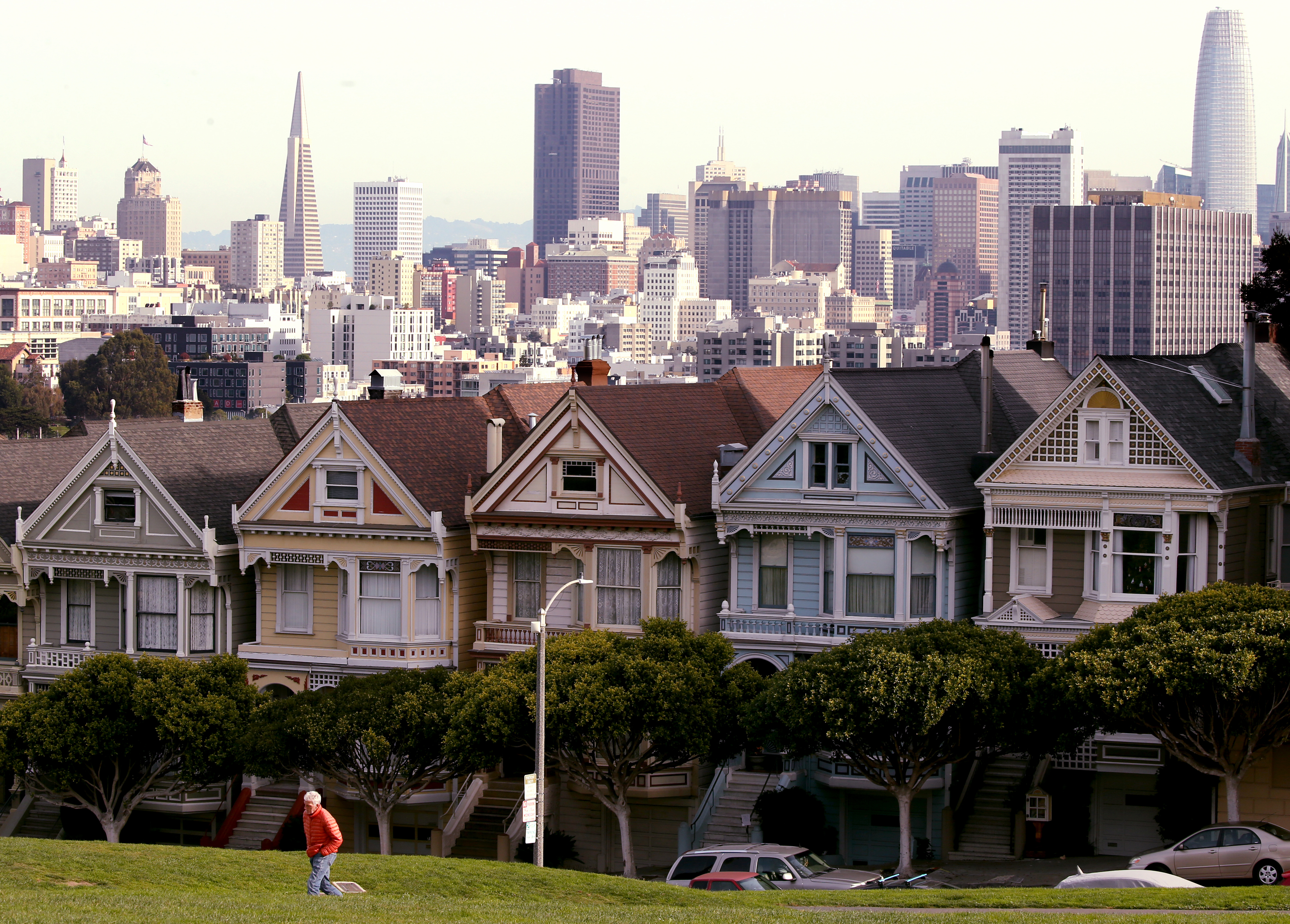 San Francisco, CA - A visitor walks through Alamo Square near ornate houses overlooking downtown San Francisco on a recent morning. Steeped in history, culture and financial and natural wealth, San Francisco attracts millions of visitors annually. However, the city by the bay now has a dubious reputation for intractable homelessness, rampant crime and an exodus of business. (Luis Sinco / Los Angeles Times)