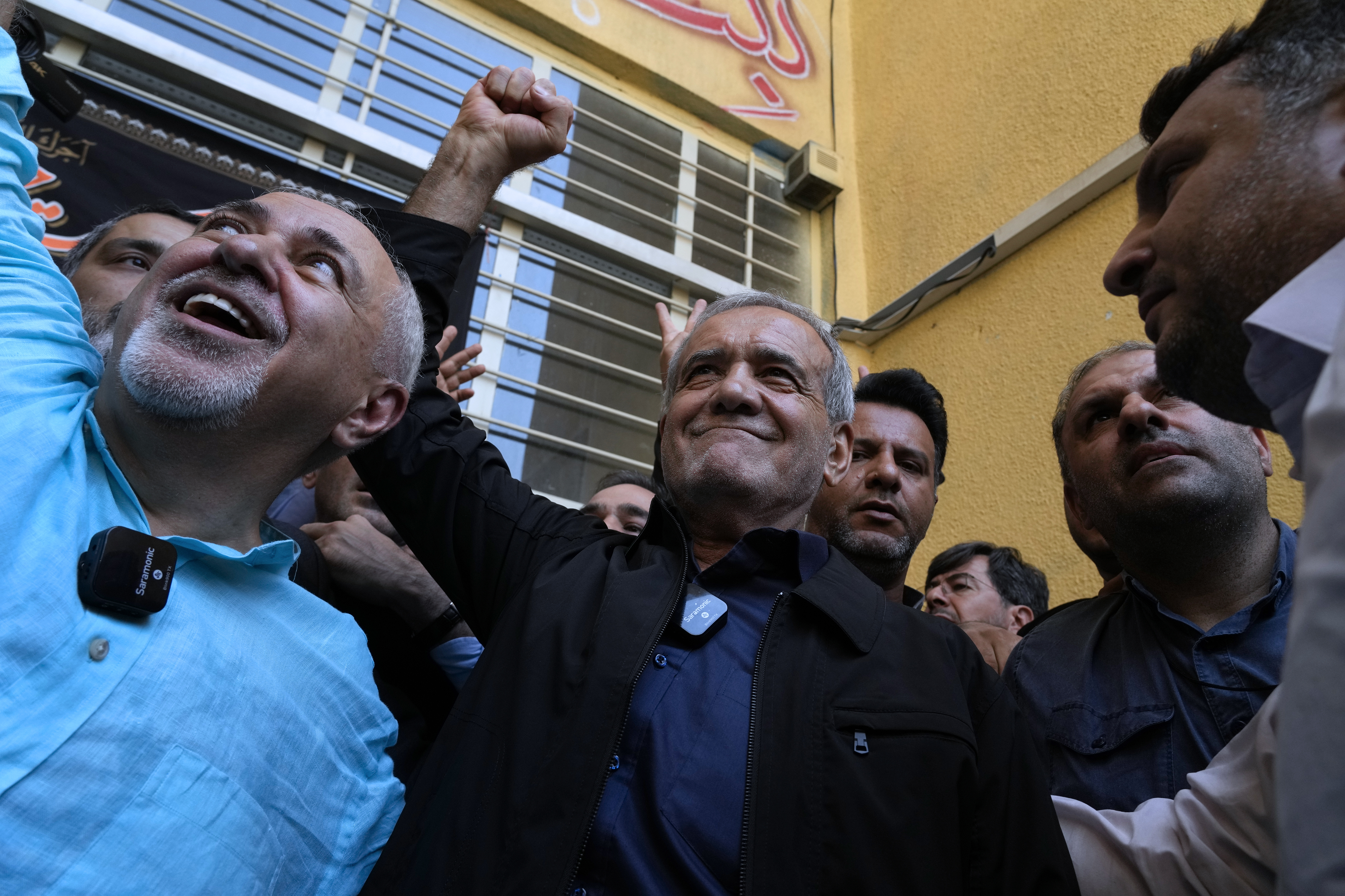 Reformist candidate for the Iran's presidential election Masoud Pezeshkian clenches his fist after casting his vote as he is accompanied by former Foreign Minister Mohammad Javad Zarif, left, at a polling station in Shahr-e-Qods near Tehran, Iran, Friday, July 5, 2024. Iranians are voting in a runoff election to replace the late President Ebrahim Raisi, who was killed in a May helicopter crash in the country’s northwest along with the foreign minister and several other officials. (AP Photo/Vahid Salemi)