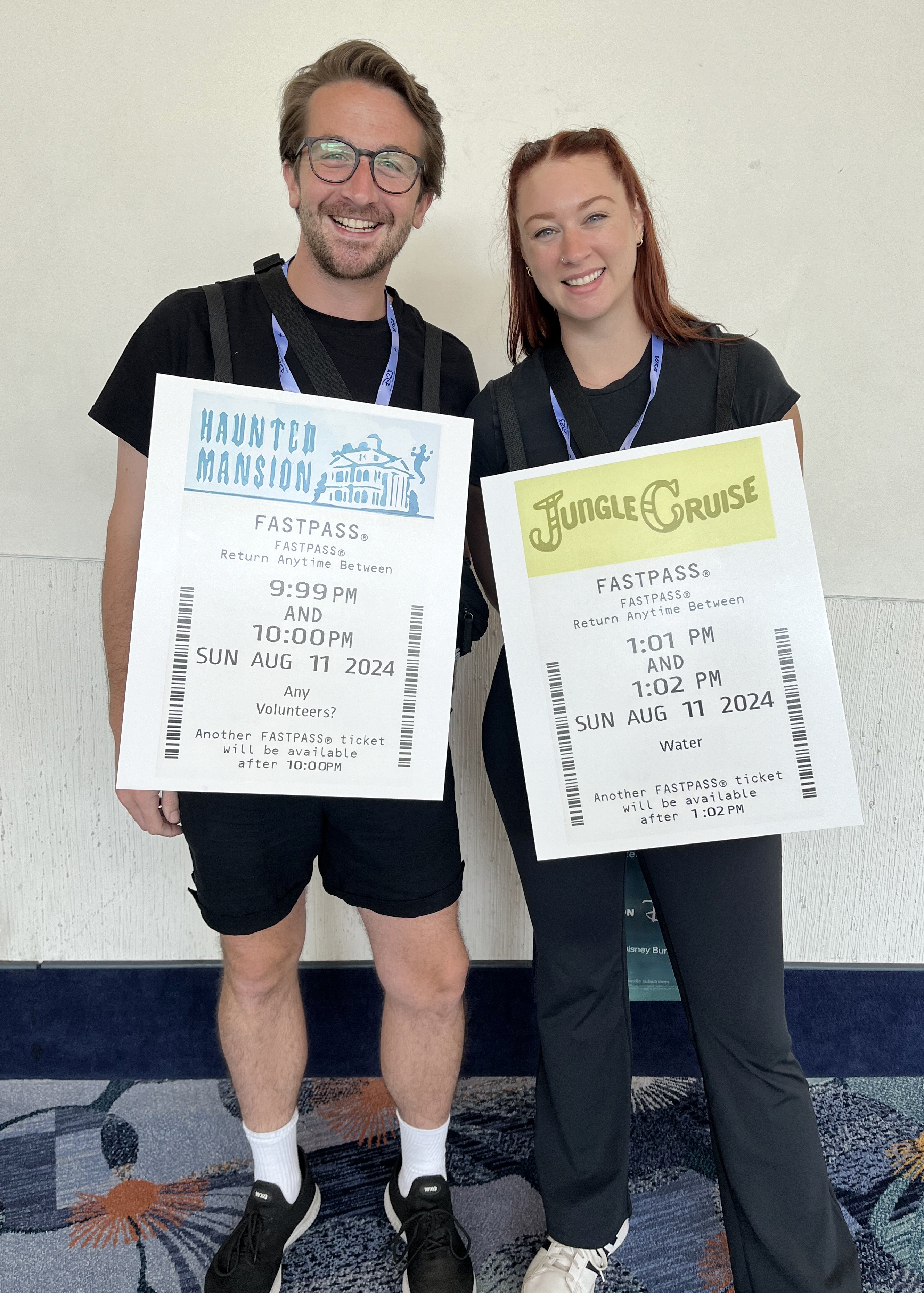 Two friends wear giant replicas of Disney FastPass on their chests at D23 fan convention.