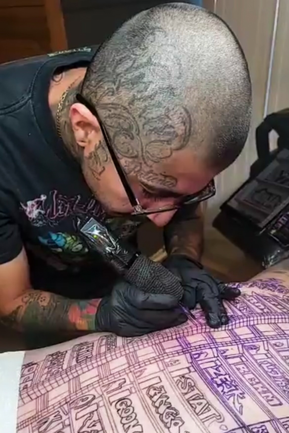 Tattoo artist Eric Reyna works on a back piece for his friend, Miguel Rodriguez, that features the graffiti covered Oceanwide Plaza.