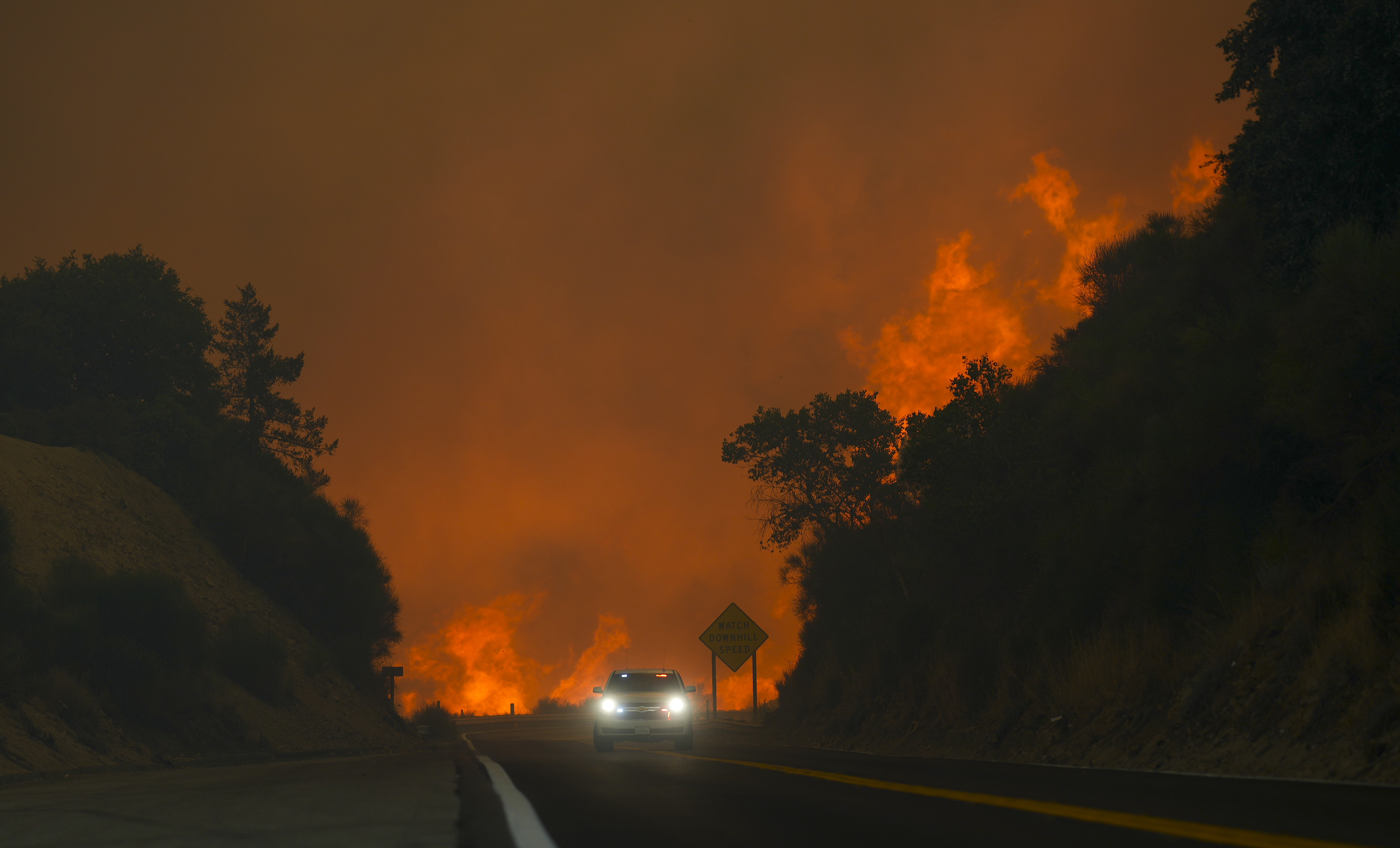 The Line Fire jumps highway 330 as a motorist speeds past Saturday, Sept. 7, 2024, near Running Springs, Calif. (AP Photo/Eric Thayer)