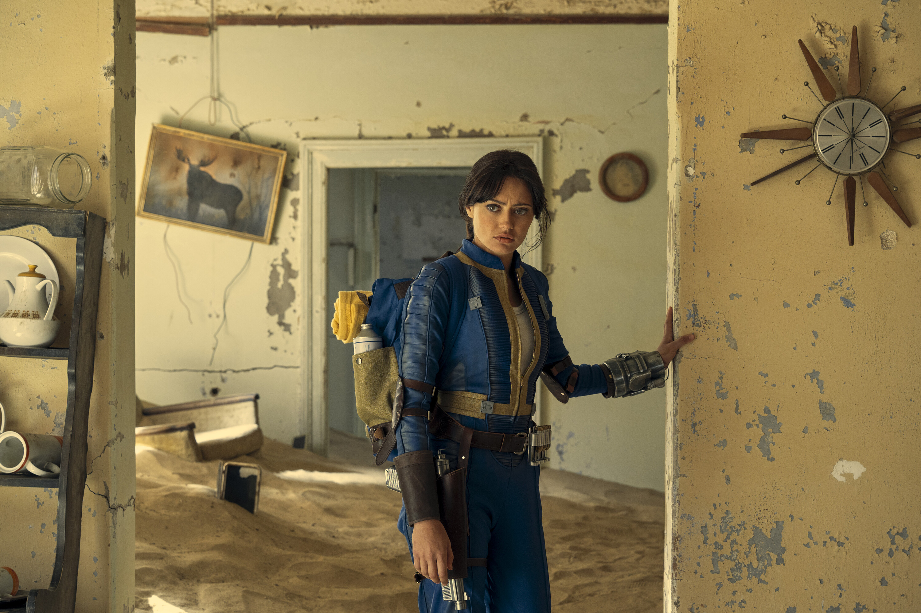 A woman stands in a doorway in a derelict abandoned building.