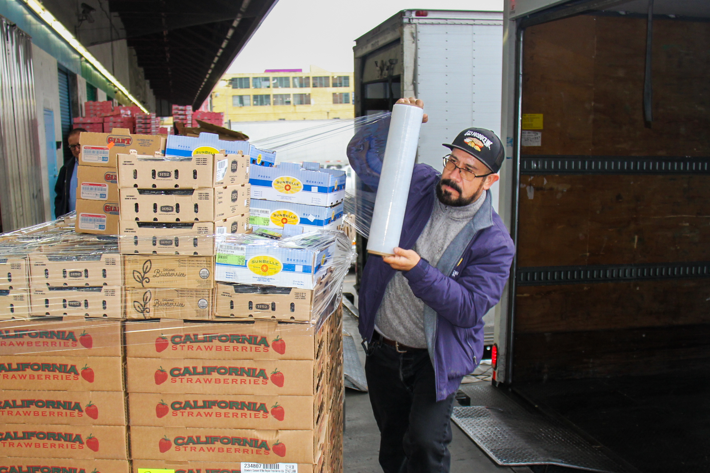 Lupe "Papi" Rodriguez uses plastic wrap to protect a large pallet of produce.