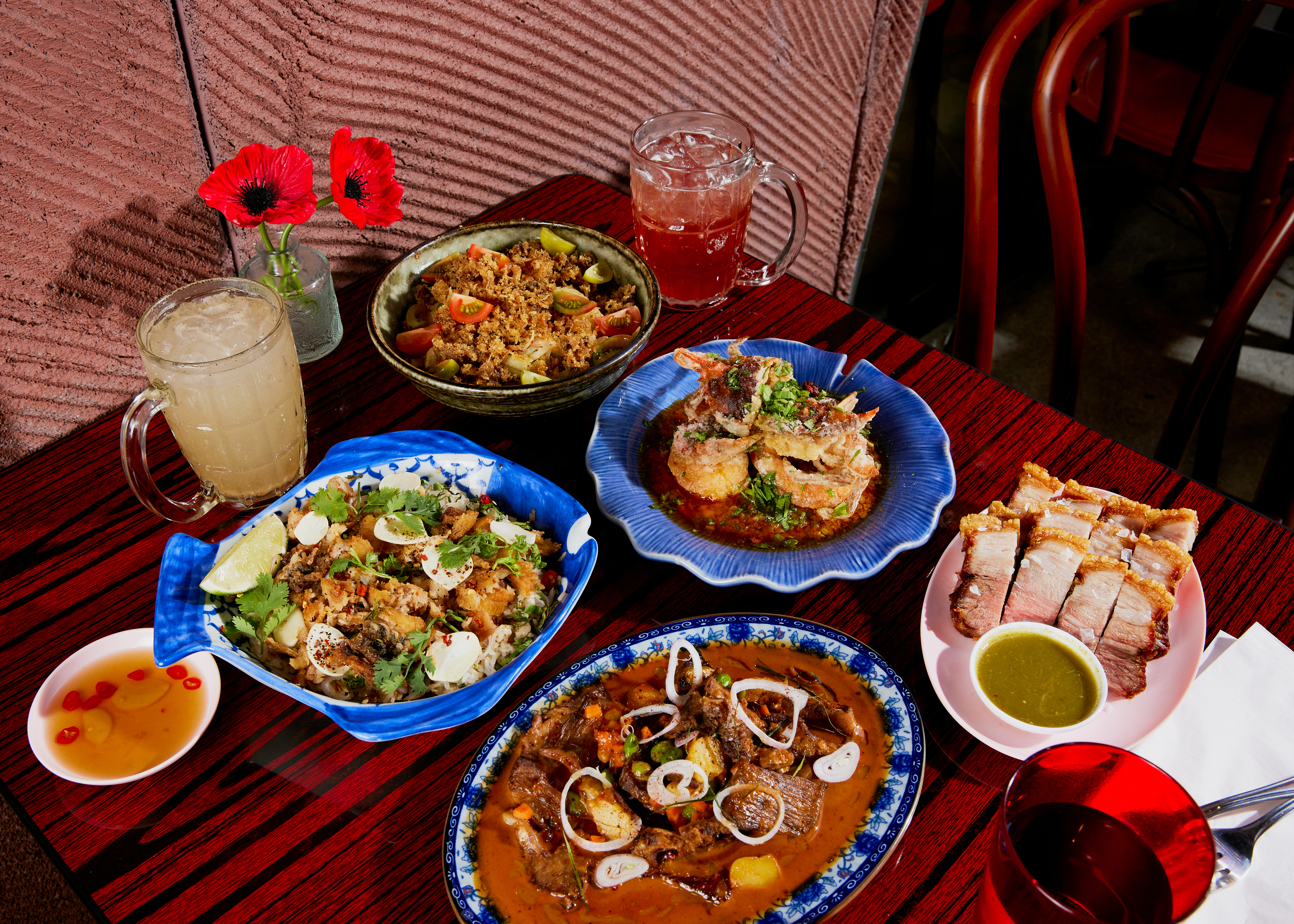 LOS ANGELES, CA - AUGUST 7, 2024: A feast of Holy Basil's signature dishes, including (clockwise from top) Papaya Salad, Soft Shell Crab with Salted Yolk, Moo Krob, Penang Short Rib, and Grandma's Fish and Rice. (Jennelle Fong / For The Times)