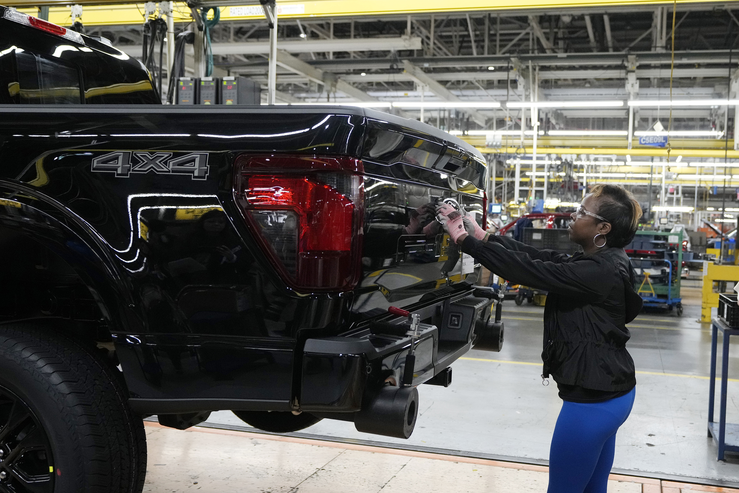 Assembly line worker Lashunta Harris applies the Ford logo on a 2024 Ford F-150 truck.