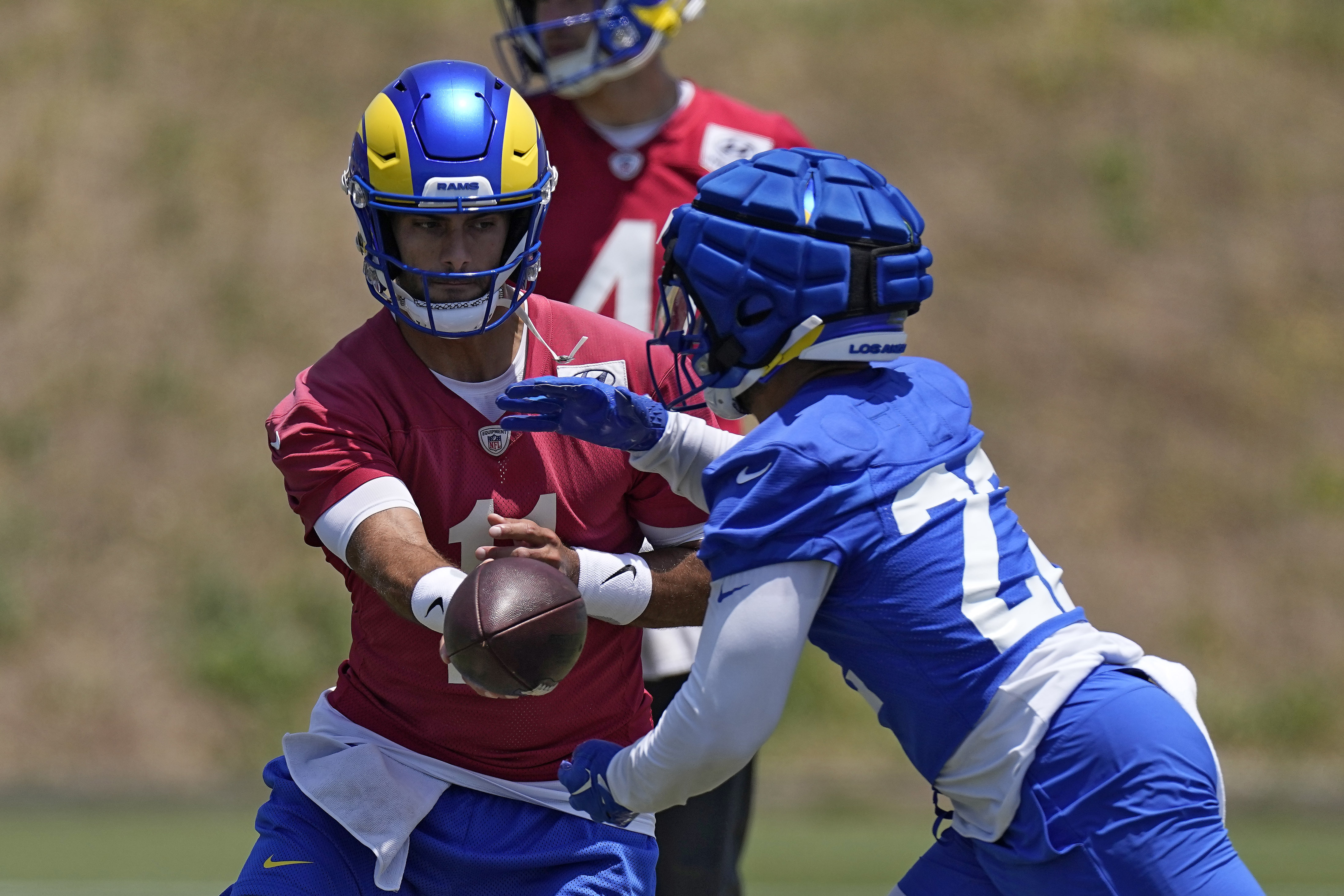 Los Angeles Rams quarterback Jimmy Garoppolo, left, hands off to running back Blake Corum during an NFL football practice Tuesday, June 4, 2024, in Thousand Oaks, Calif. (AP Photo/Mark J. Terrill)