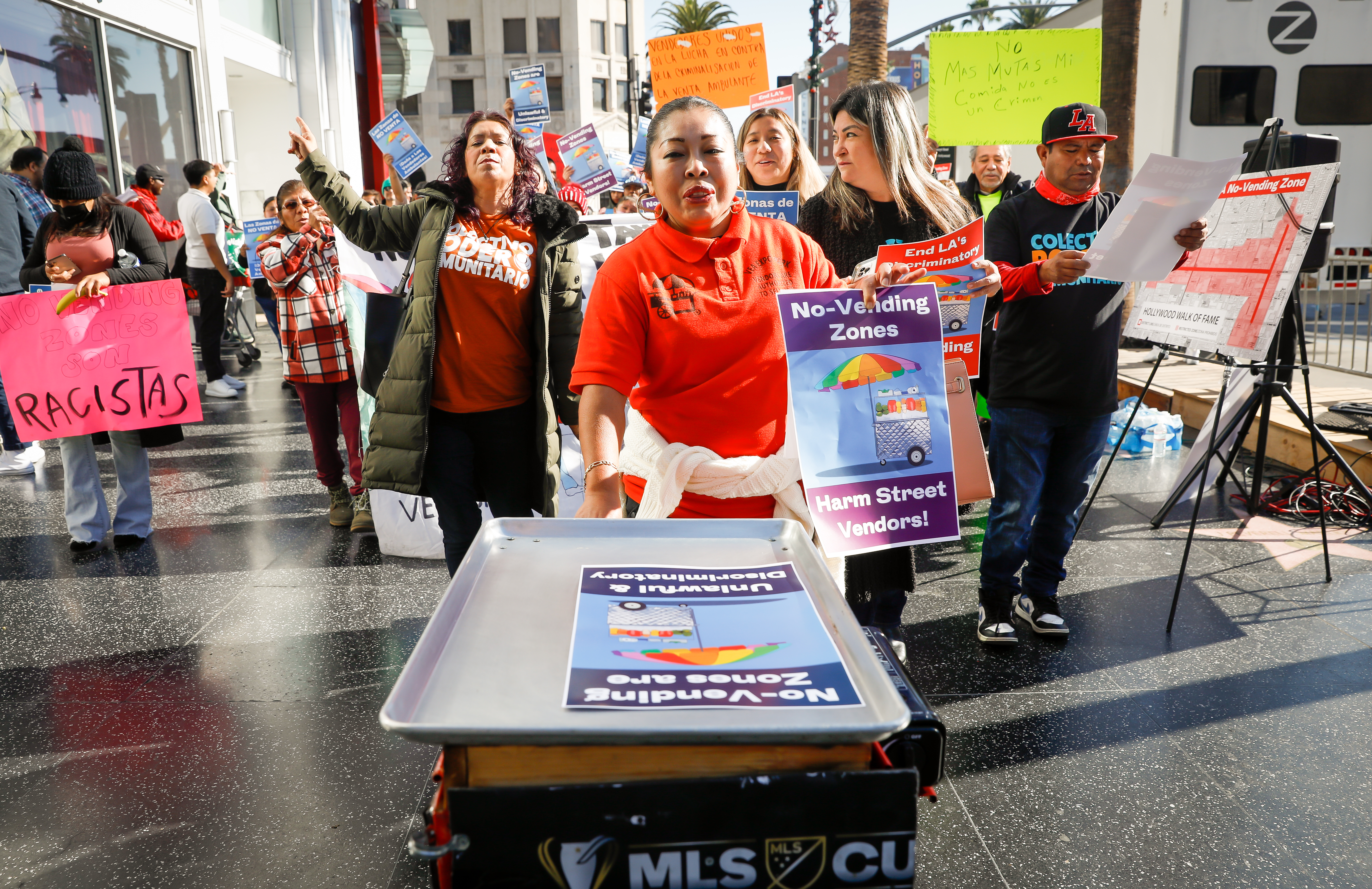 HOLLYWOOD-CA - DECEMBER 8, 2022: Street Vendors including Hermenegilda Garcia, center, who sells hot dogs in Exposition Park, along with supporters gather on Hollywood's Walk of Fame to demonstrate against an LA city ordinance created of eight citywide no vending zones, on Thursday, December 8, 2022. (Christina House / Los Angeles Times)