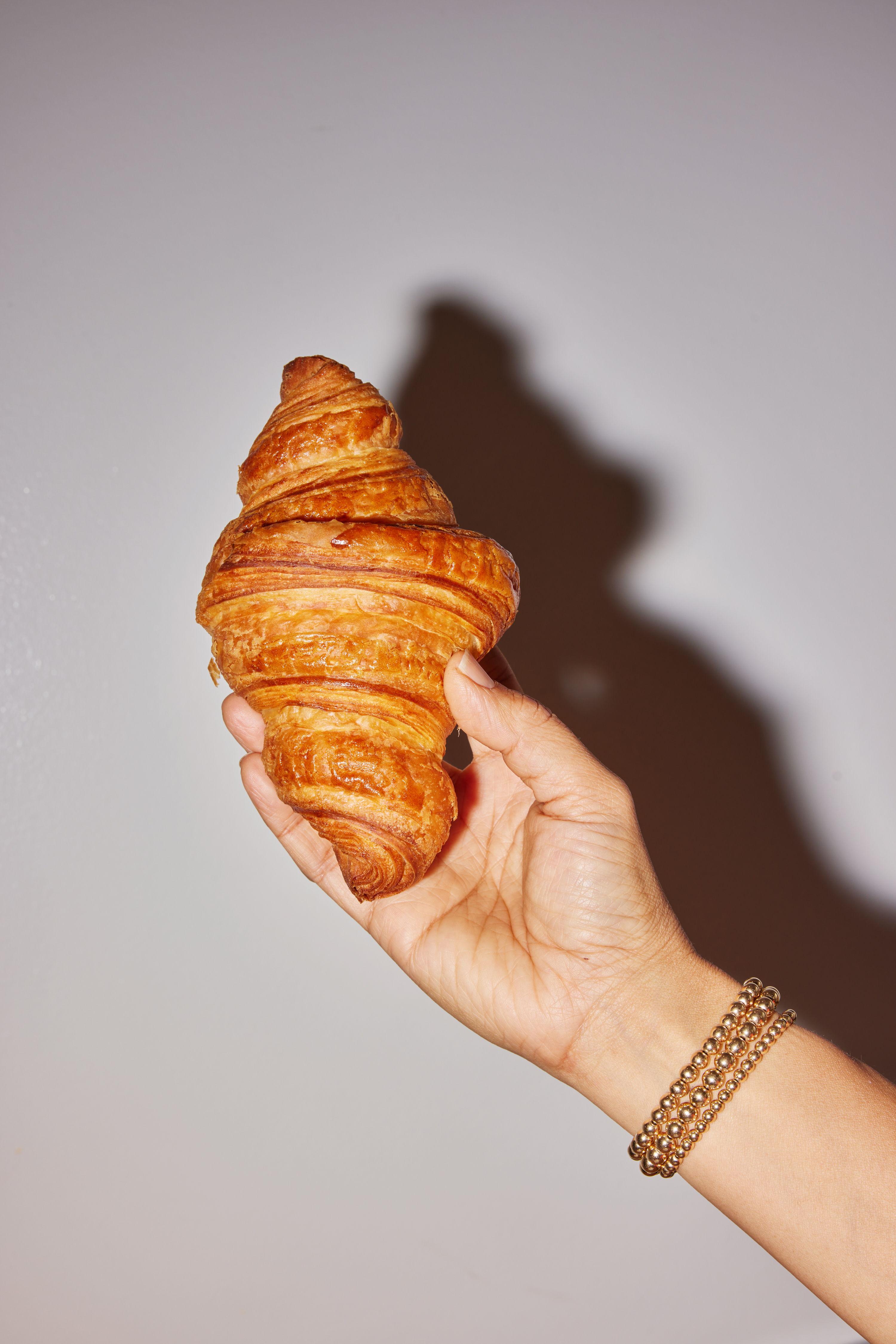 A hand holds up a croissant