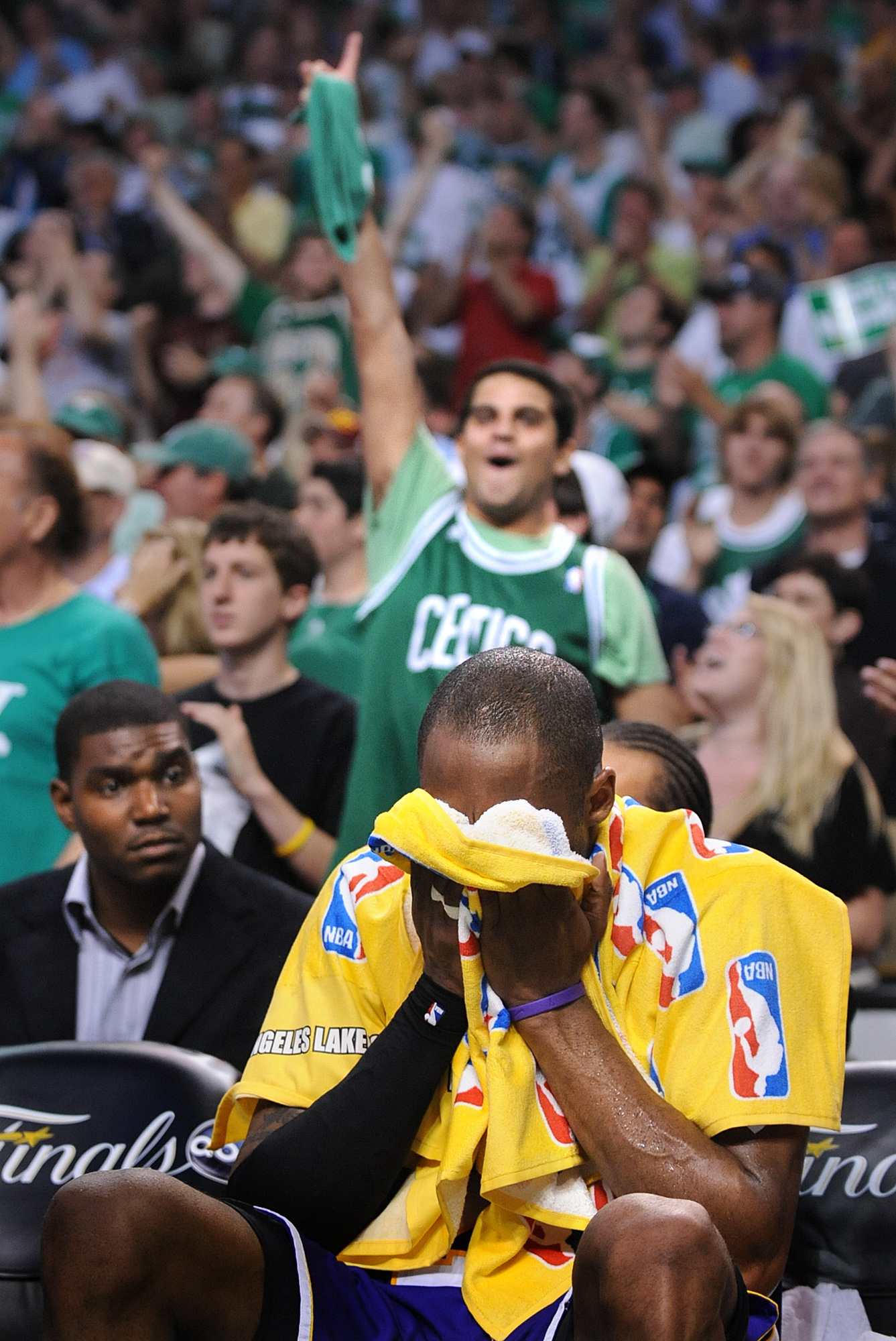 Celtics fans celebrate a playoff win as Kobe Bryant sits on the bench and puts his head in a towel in Boston on June 8, 2008.