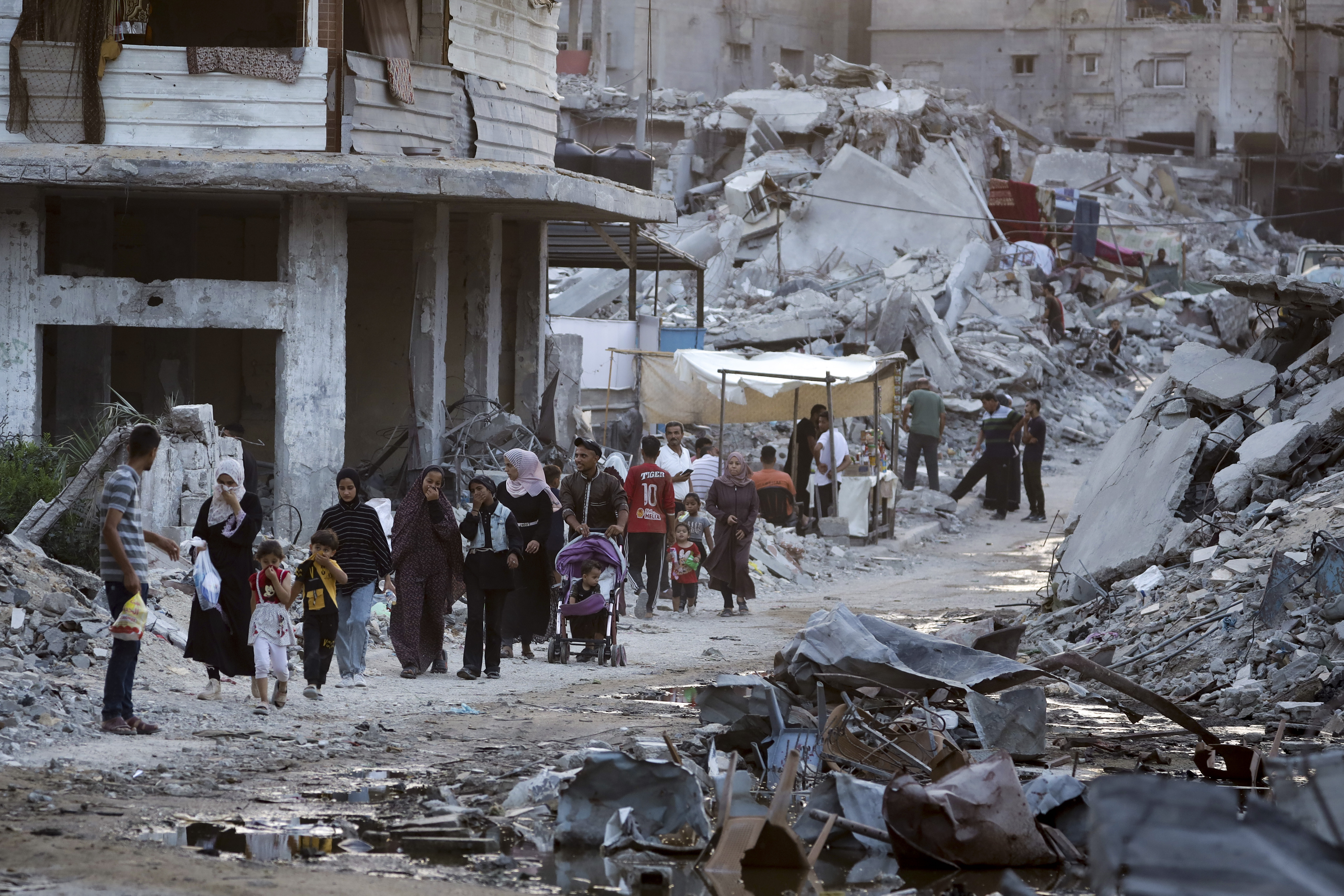 FILE - Palestinians displaced by the Israeli air and ground offensive on the Gaza Strip walk next to sewage flowing into the streets of the southern town of Khan Younis, Gaza Strip, July 4, 2024. Hamas has given initial approval for a U.S.-backed proposal for a phased cease-fire deal in Gaza, dropping a key demand that Israel gives an up-front commitment for a complete end to the war, a Hamas and an Egyptian official said Saturday July 6, 2024. (AP Photo/Jehad Alshrafi, File)