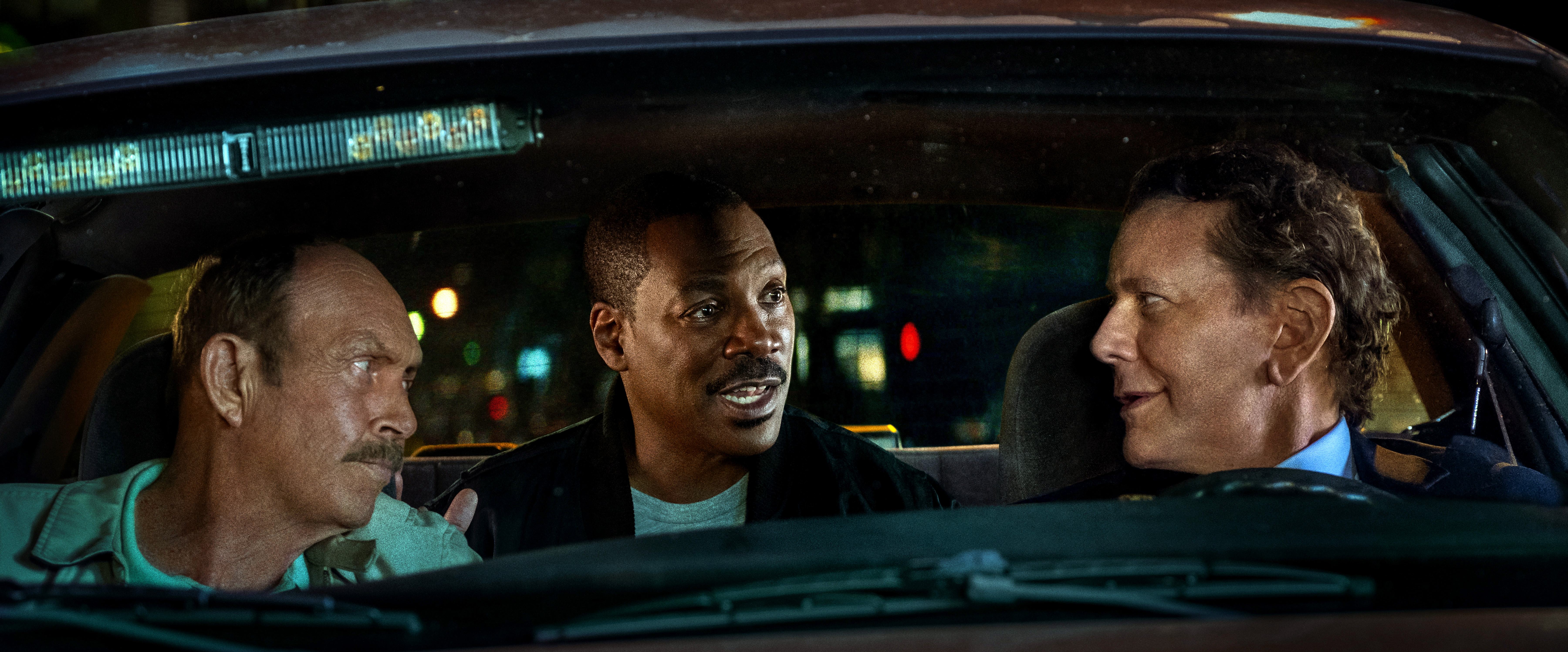 A still from a movie showing three men in a car