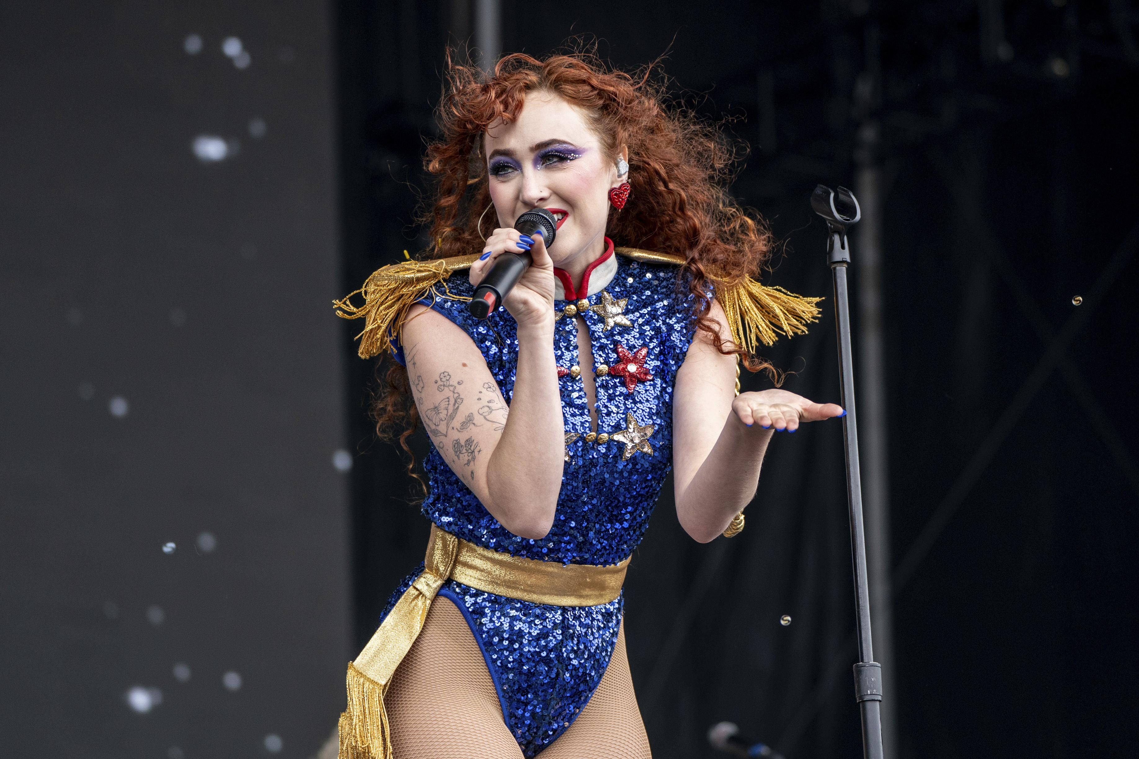 Chappell Roan singing into a mic wearing blue sequinted leotard. 