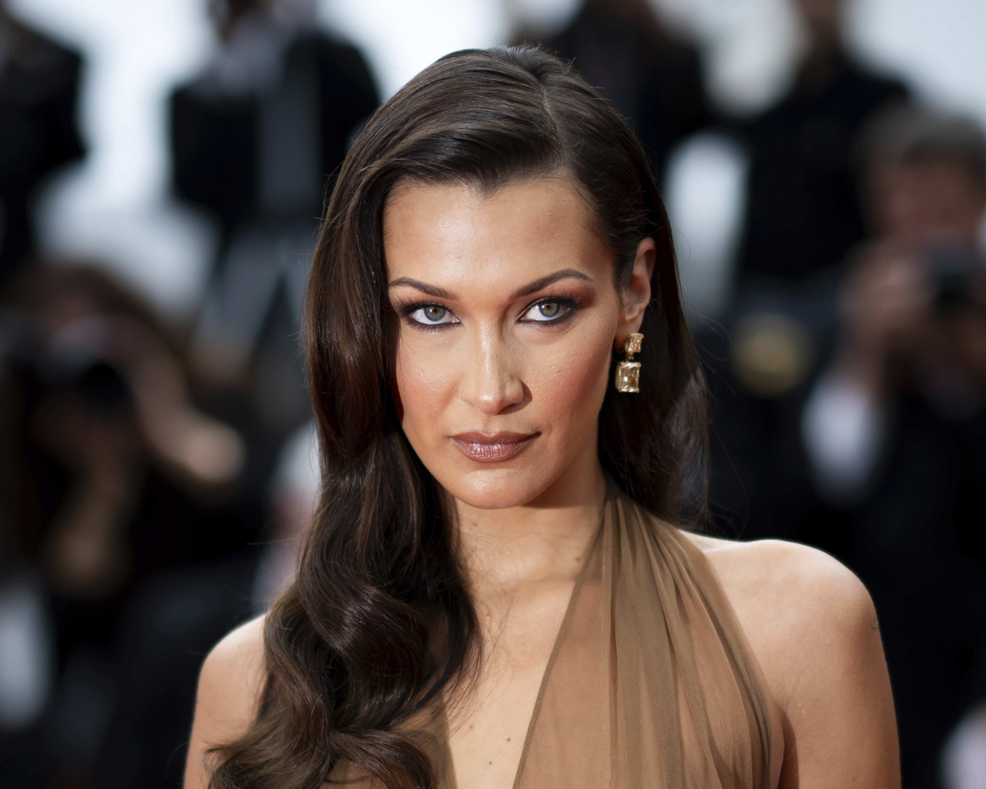 Bella Hadid gazing upward in a brown halter top with her brown hair parted to the side.