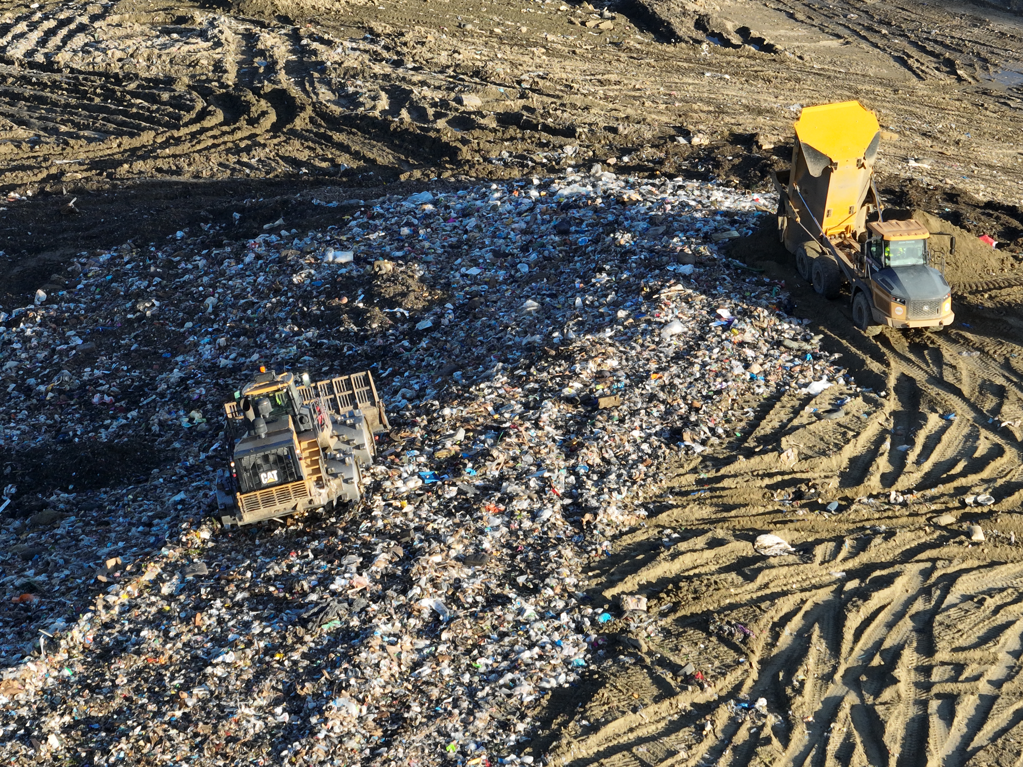 Castaic, CA - February 22: An aerial view of trucks unloading, heavy equipment spreading trash over a hill near where 100 metal storage containers storing contaminated or polluted water, holding up to 20,000 gallons each as the result of an underground landfill fire at Chiquita Canyon Landfill in Castaic Thursday, Feb. 22, 2024. Around 200,000 gallons of the contaminated water is coming out of the landfill each day. Environmental regulators have found elevated levels of cancer causing Benzine in the polluted water spilling onto the surface of the landfill. Landfill operators are also constructing a drainage system to capture the contaminated water that is spilling onto the surface and proactively pumping the water. Residents of Val Verde and Castaic are protesting to call for Chiquita Canyon Landfill to be closed in Hasley Canyon Park in Castaic. Garbage has been burning deep inside the landfill due to a chemical reaction for much of the past year, and recently scalding-hot contaminated water has surged to the surface. The protest follows calls from the County Supervisor Kathryn Barger's office, which said the landfill should provide funds to relocate residents who want to temporarily move until the issue is resolved. (Allen J. Schaben / Los Angeles Times)