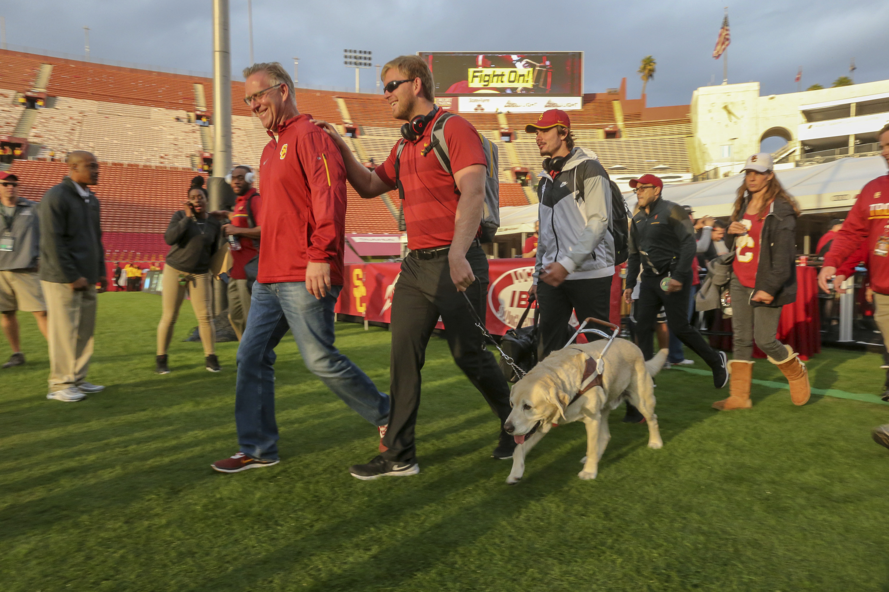 USC long snapper Jake Olson walks on a football field with the aid of his service dog, Quebec