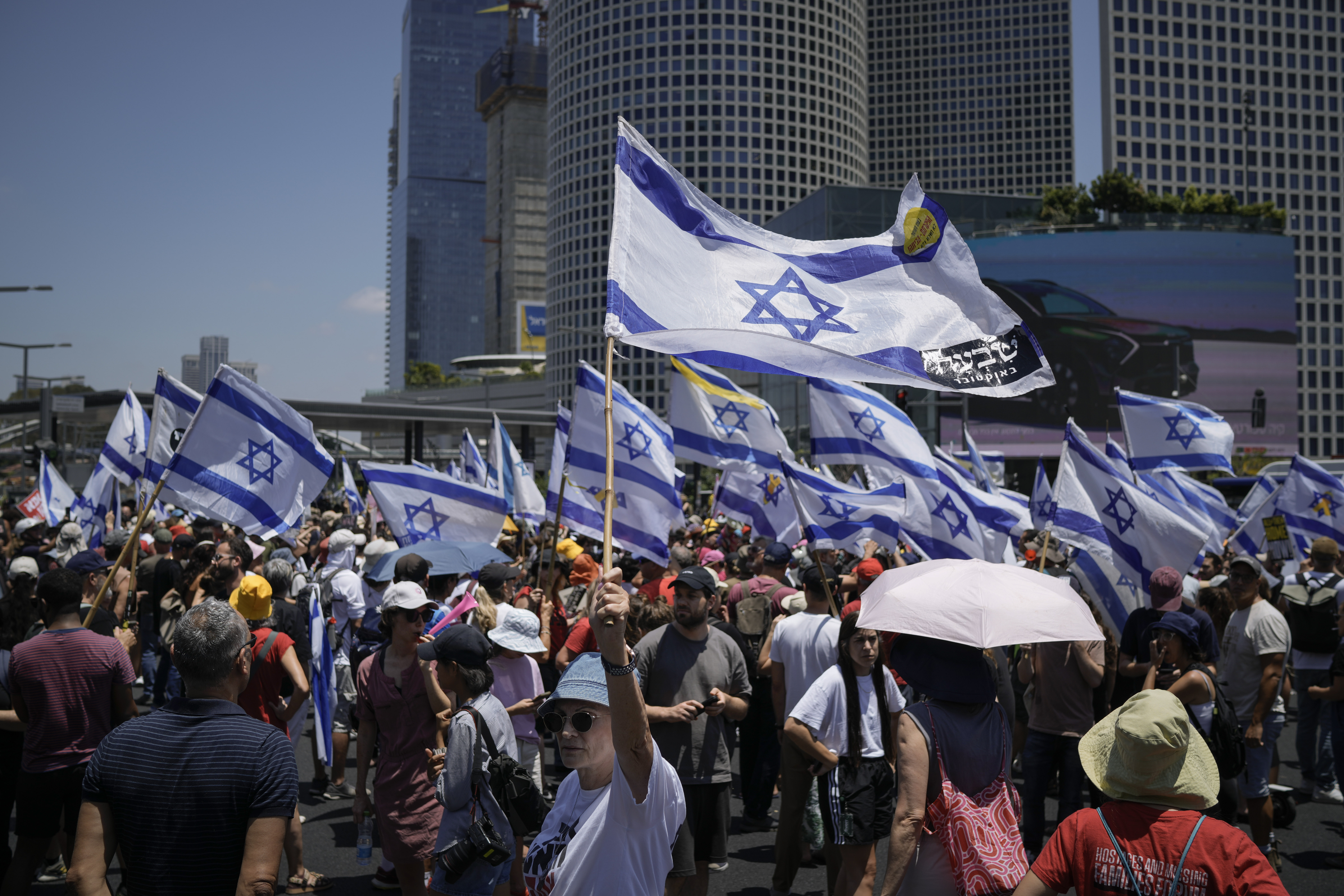 Demonstrators wave Israeli flags during a protest marking nine months since the start of the war and calling for the release of hostages held in the Gaza Strip by the Hamas militant group, in Tel Aviv, Israel, Sunday, July 7, 2024. (AP Photo/Leo Correa)