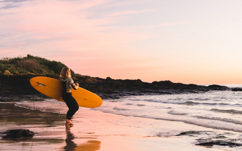 surfer on beach with board watching waves