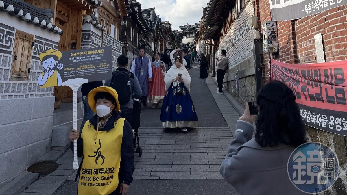 北村韓屋村因為遊客眾多，就有工作人員舉牌提醒控制音量，避免影響居民。（圖／鏡週刊）