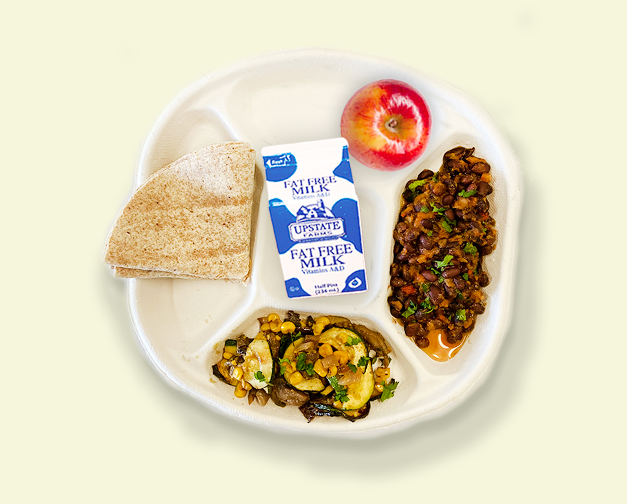 Plate of school food with low fat milk, stewed beans, zucchini with corn, an apple, and a whole wheat tortilla