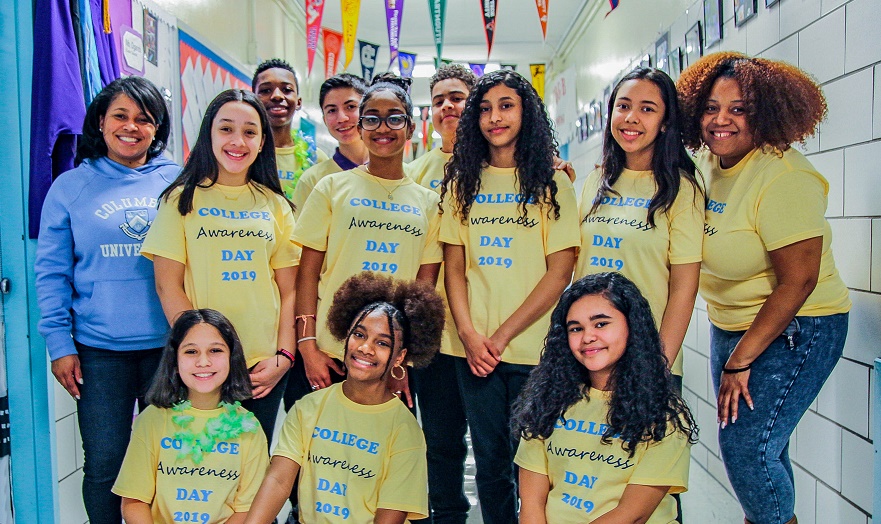 Students gathered in a hallway in a school with yellow tee shirts that say 